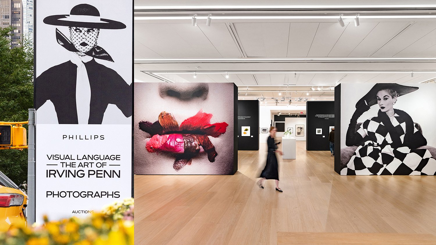 Interior of an art gallery exhibiting photographs by Irving Penn, including large black and white portraits of women, with a sign outside advertising the exhibition.