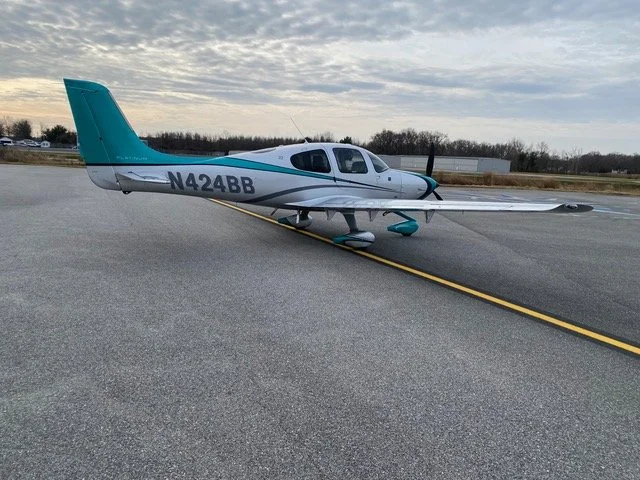 Single-engine airplane on a runway with a cloudy sky.