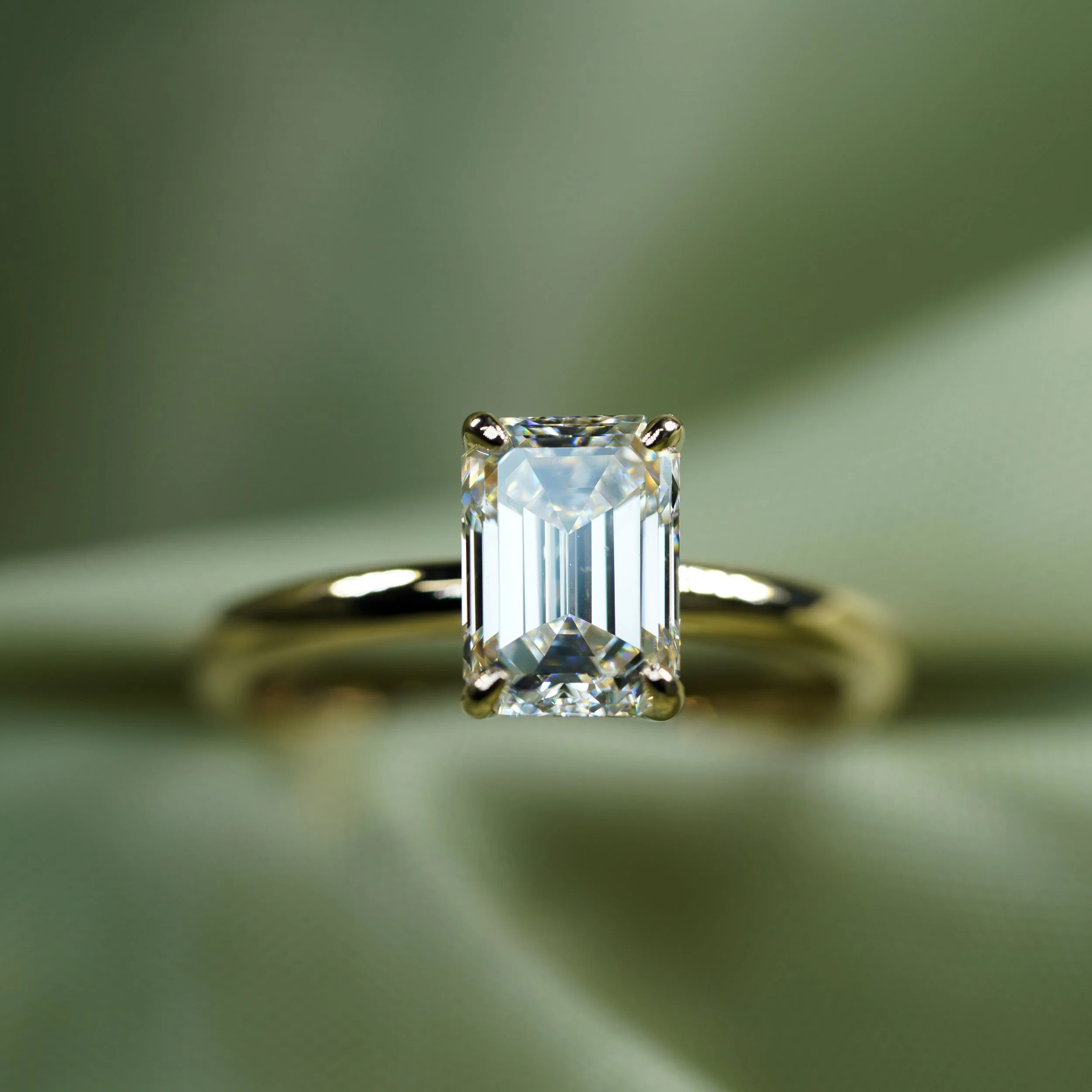 Anillo solitario de oro amarillo con diamante central de corte esmeralda.