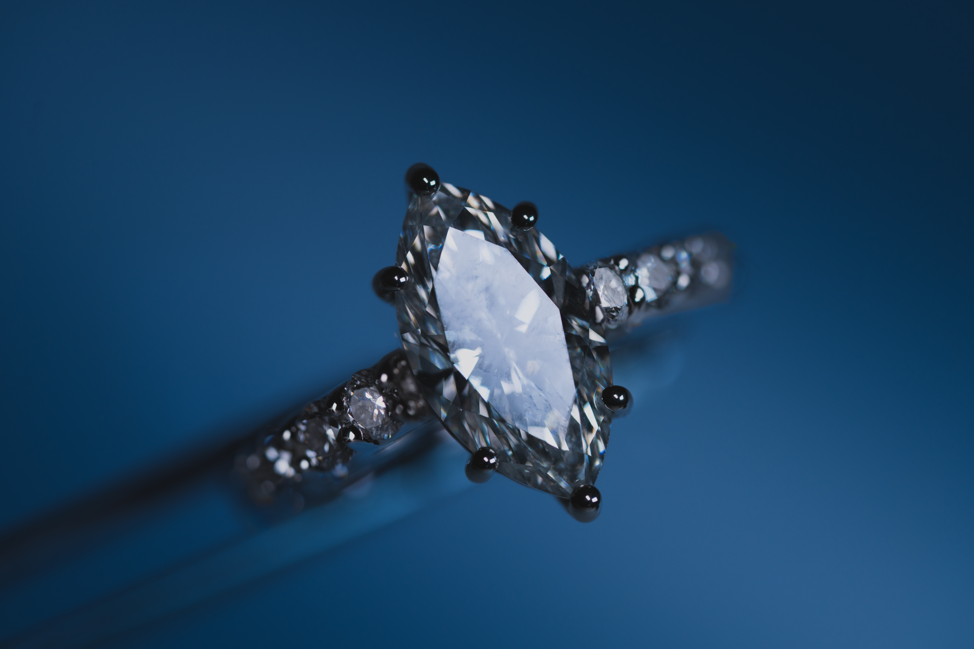 Anillo de compromiso en oro blanco con diamante central de corte marquesa y diamantes laterales que aportan brillo y elegancia al diseño.
