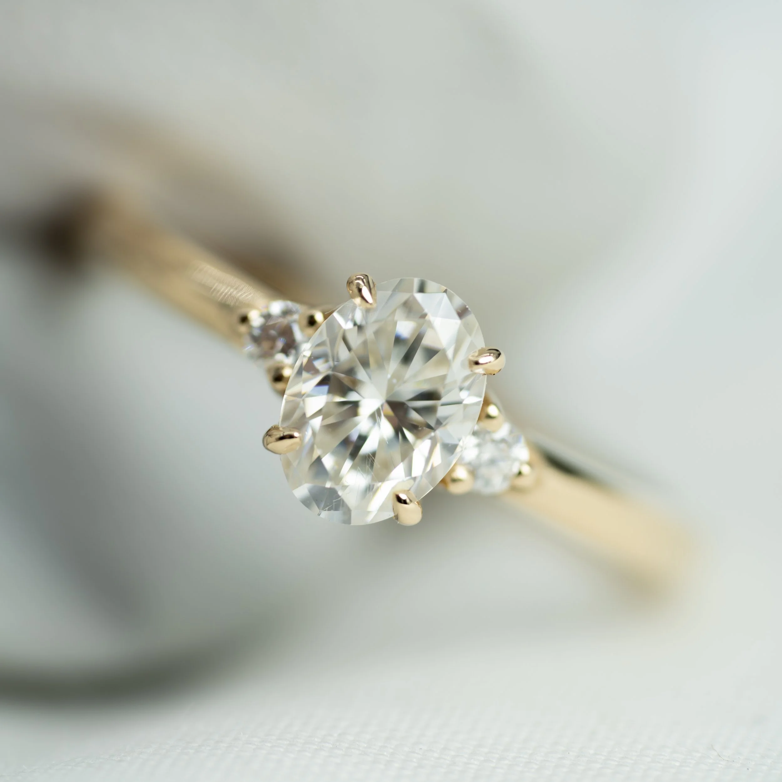 Anillo trilogía en oro amarillo de 14K con diamante central corte oval y diamantes laterales de corte redondo.