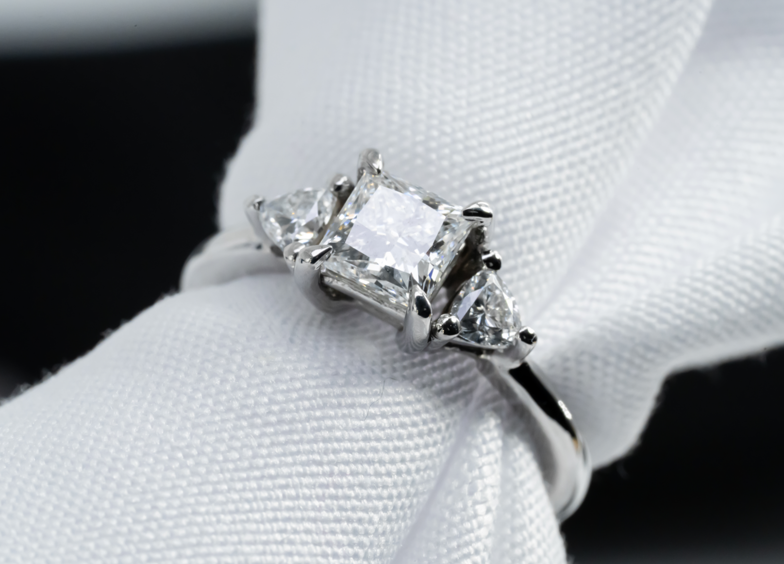 Anillo trilogía en oro blanco con diamante central de corte princesa y diamantes laterales de corte trillion.