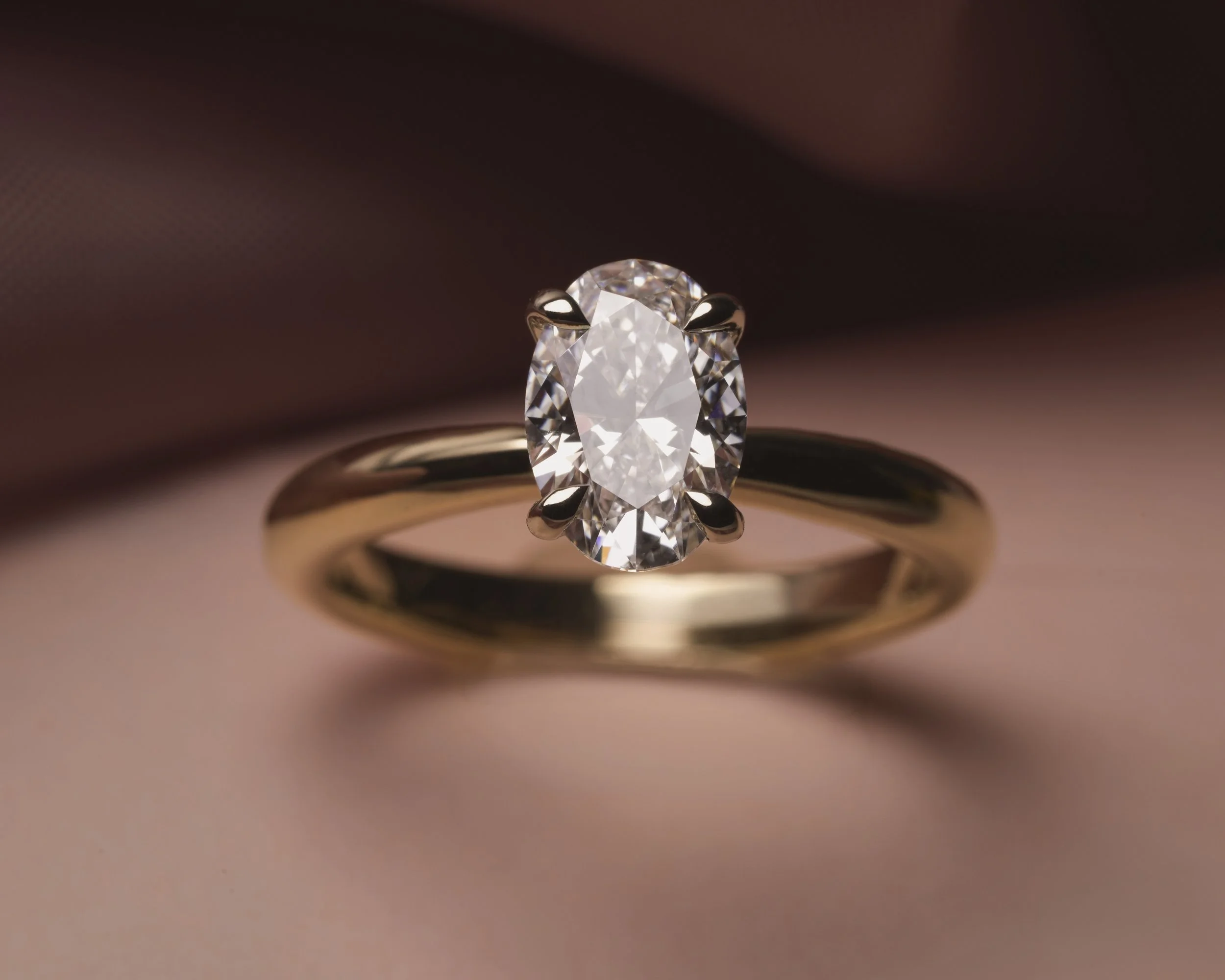 Anillo solitario de oro amarillo con diamante central de corte oval.