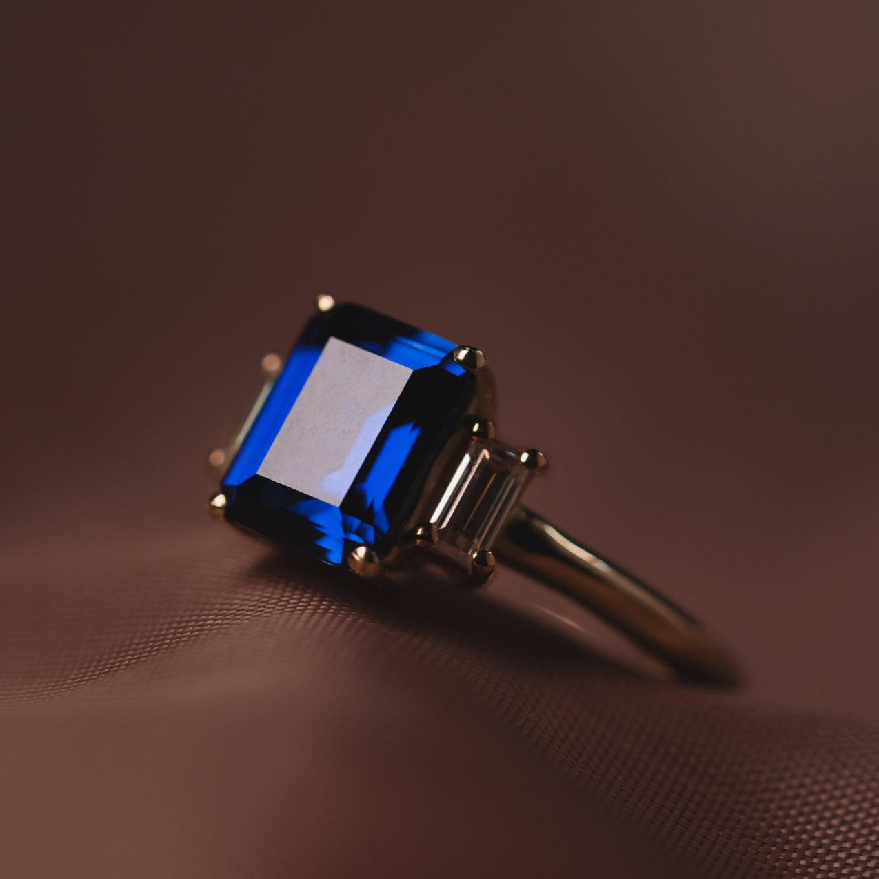 Anillo de trilogía con zafiro central corte esmeralda y diamantes laterales corte baguette, diseño de Pérez Filoteo.