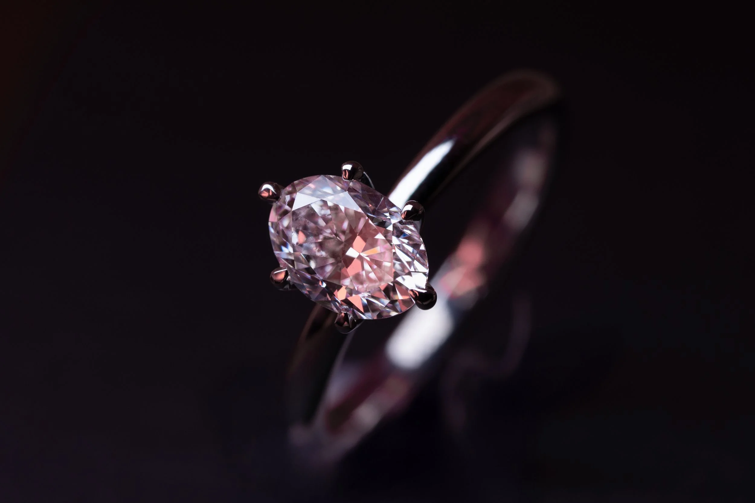 Anillo solitario de oro blanco con diamante central de corte oval.