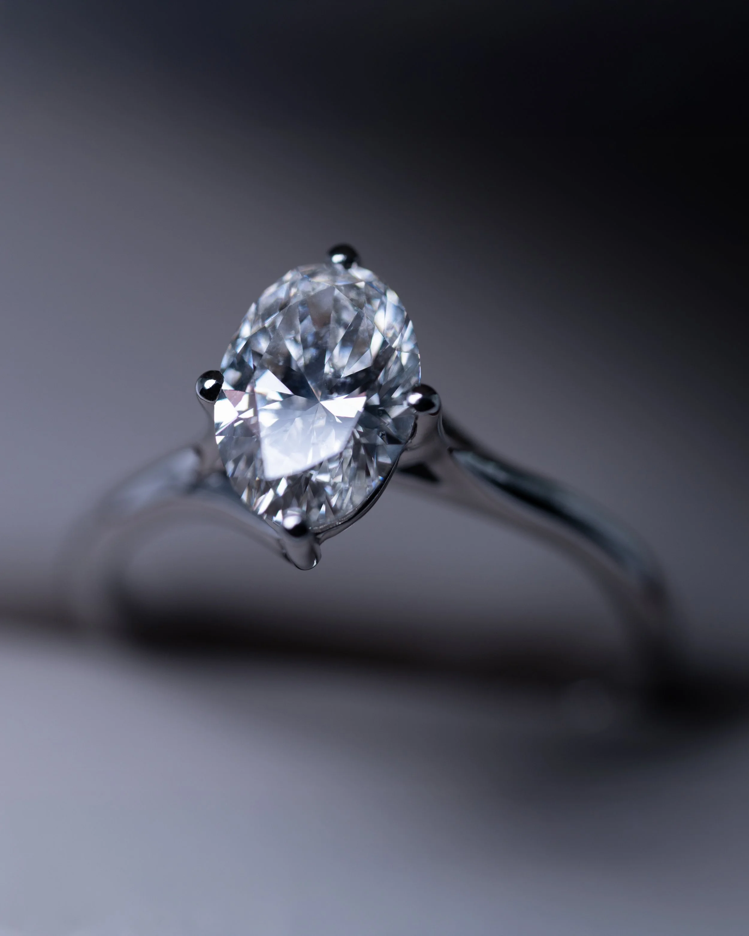 Anillo solitario de oro blanco con diamante central de corte oval.