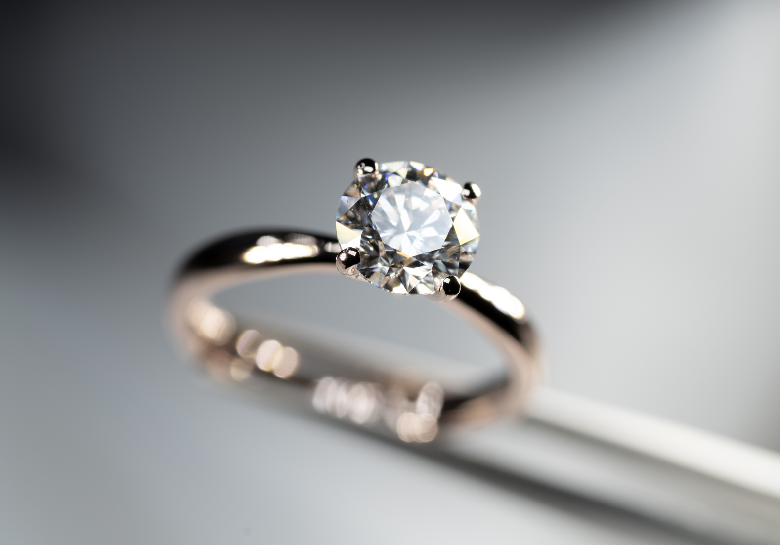Anillo solitario de oro rosa con diamante central de corte redondo.
