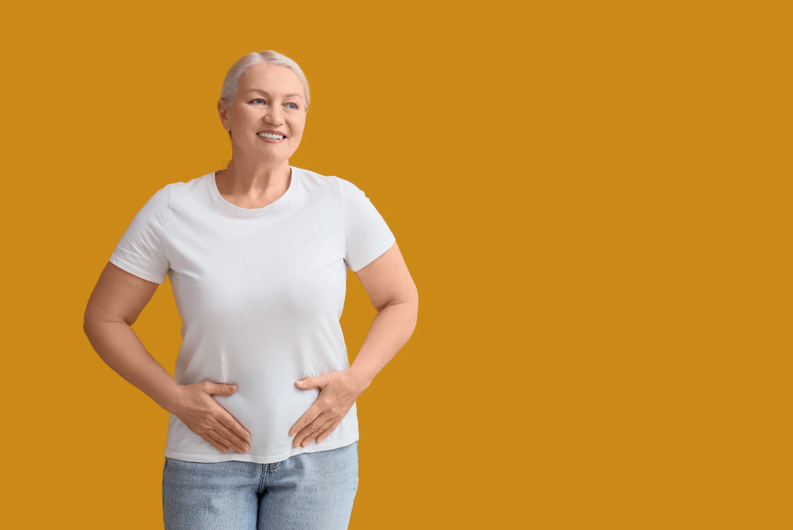 Aging woman smiling and holding her stomach, symbolizing aging and the digestive system.
