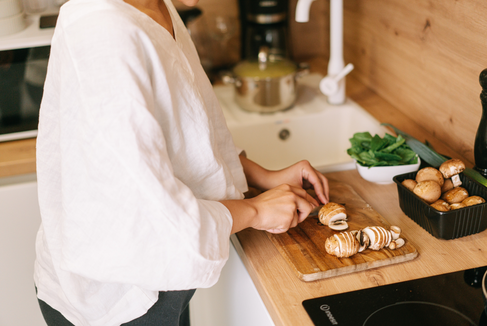 Person slicing mushrooms in a kitchen, preparing foods that support a healthy gut