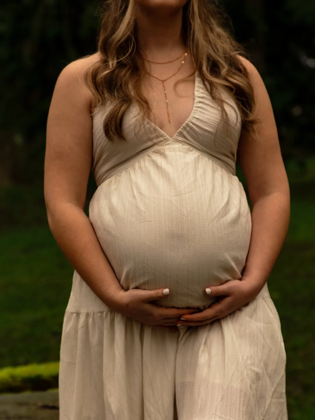maternity client holding her belly in a beige cotton linen dress