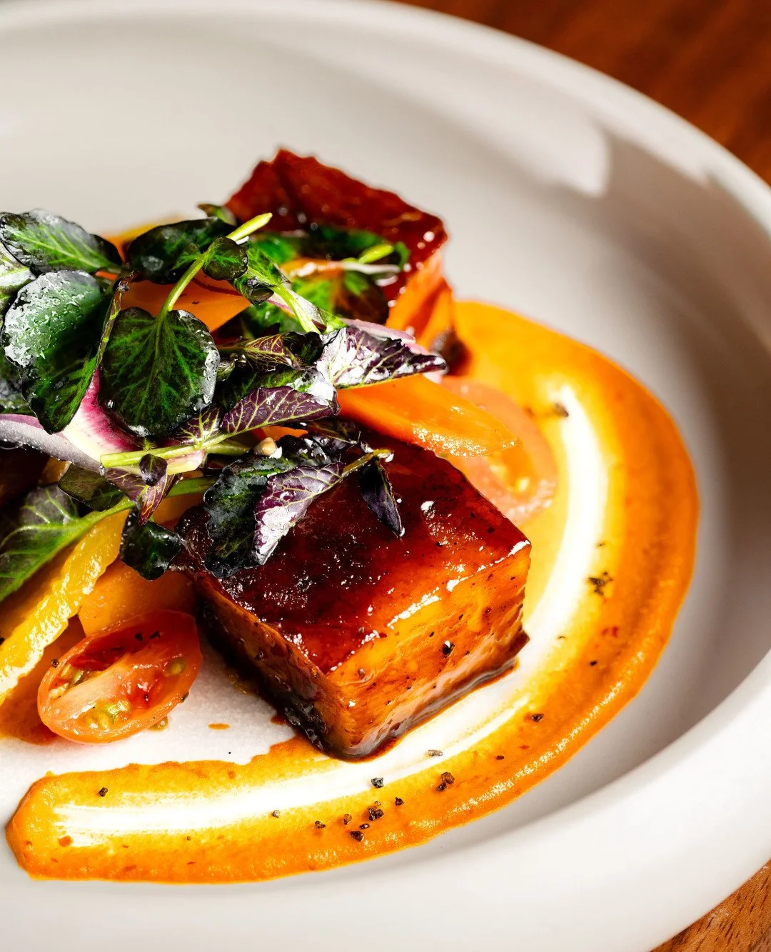 Slow-cooked pork belly with a chipotle glaze, paired with peanut red pipi&aacute;n, crisp watercress, and pickled vegetables for a rich contrast of heat, nuttiness, and brightness.