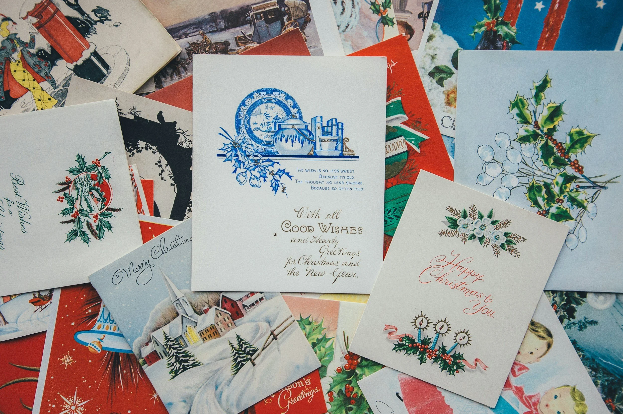 A Christmas card featuring a sleigh with a decorative scrollwork design, set against a winter scene with white birch trees and snowflakes.