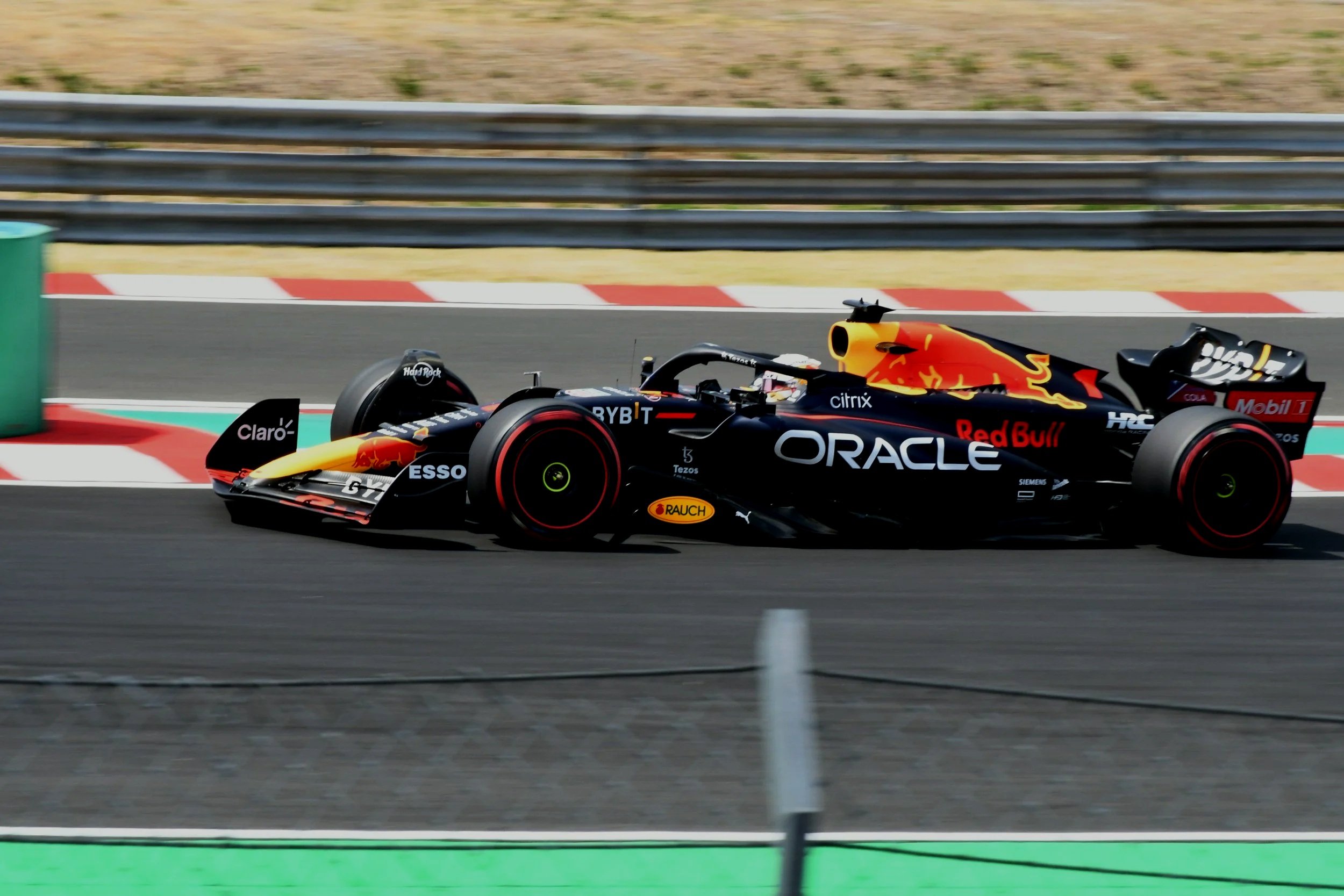 A Red Bull Racing Formula 1 car speeding on a racetrack, with sponsor logos like Oracle, Red Bull, and Claro visible.
