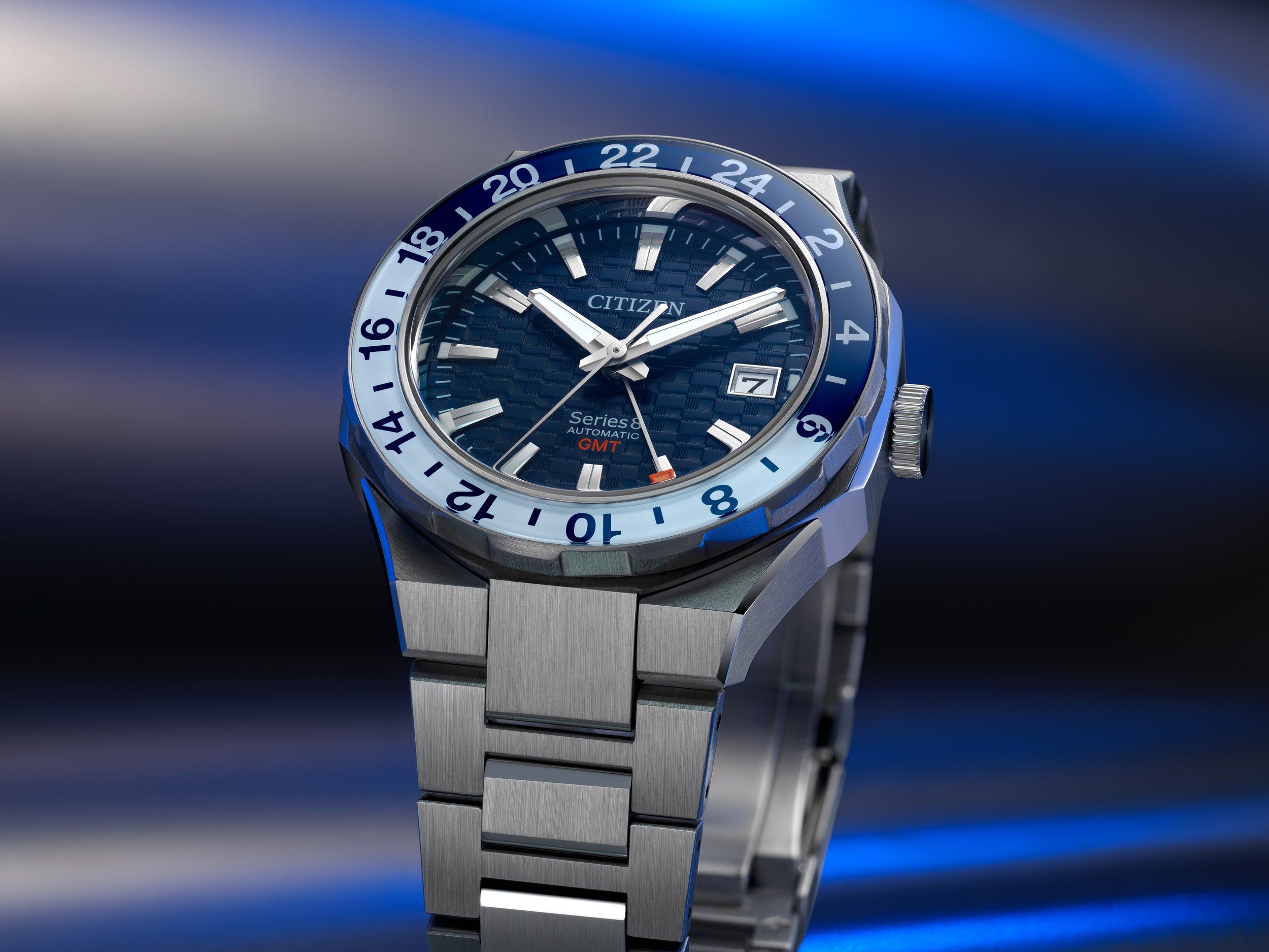 A close-up of a Citizen Series 8 automatic GMT wristwatch with a blue textured dial, stainless steel bracelet, and a rotating bezel with 24-hour markings.