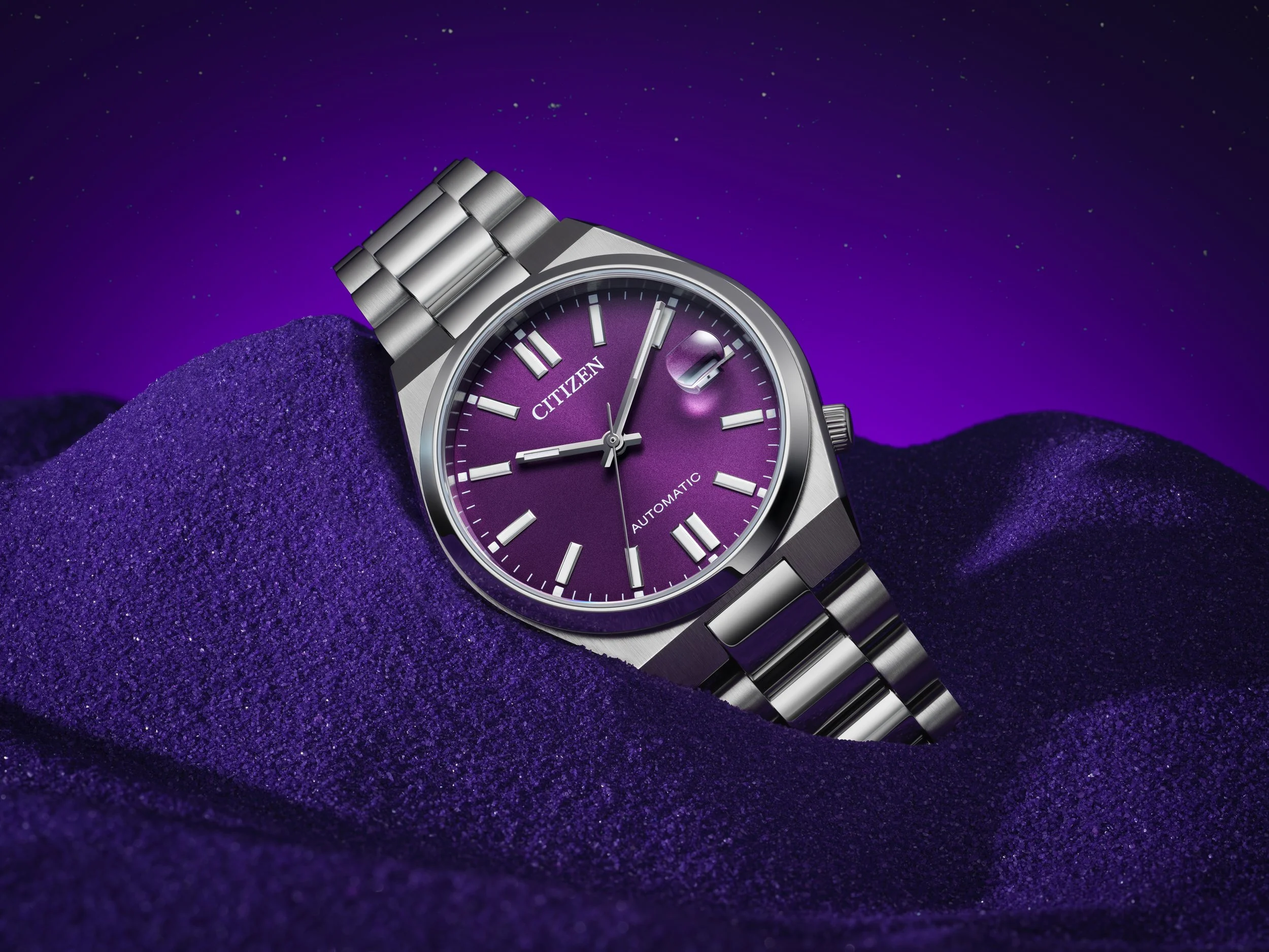 A silver Citizen wristwatch with a purple face and a date window, resting on purple glittery fabric with a purple night sky background filled with stars.