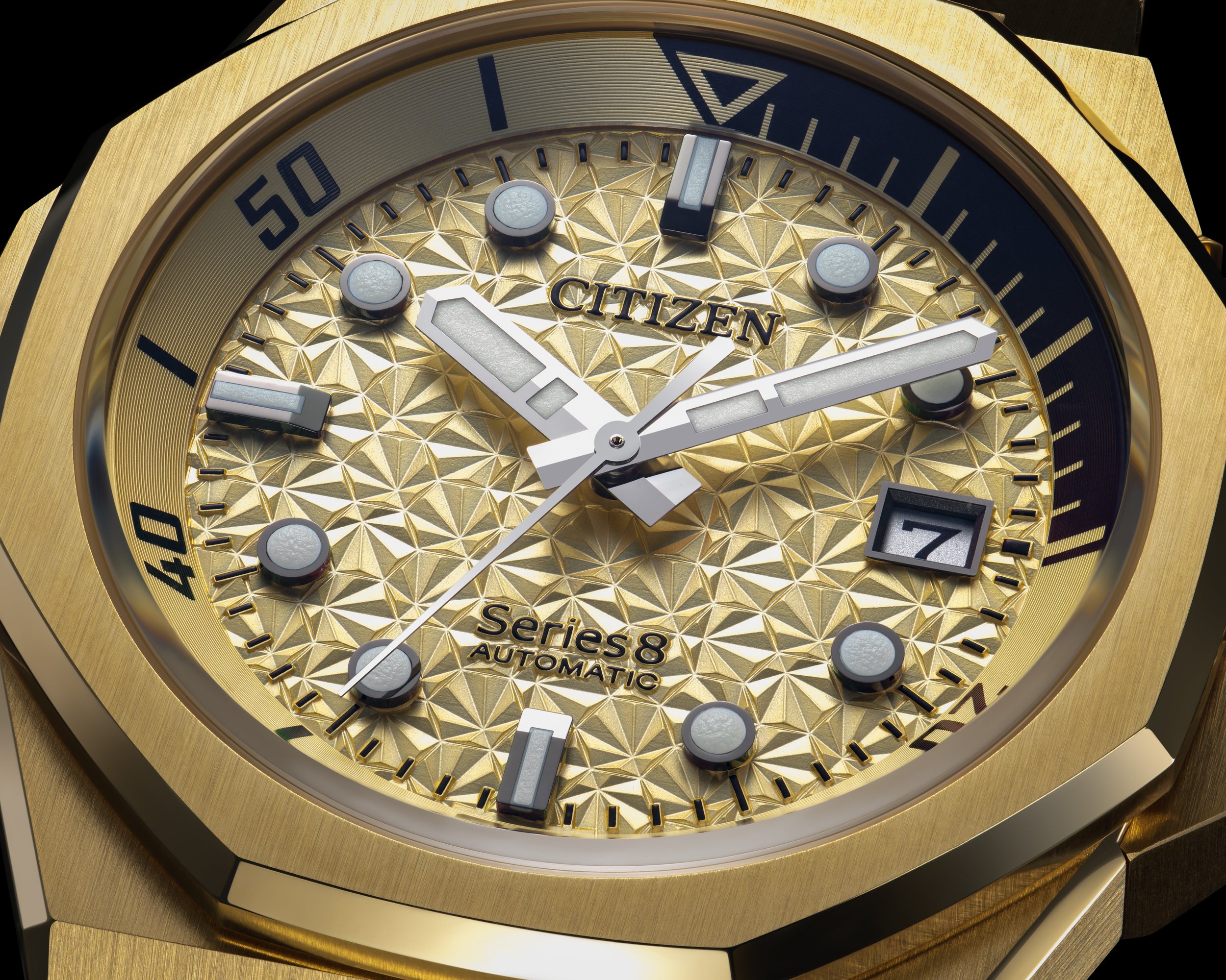 Close-up of a gold Citizen Series 8 automatic wristwatch with a textured gold dial, silver hour and minute hands, a seconds hand, and a date window showing the number 7.
