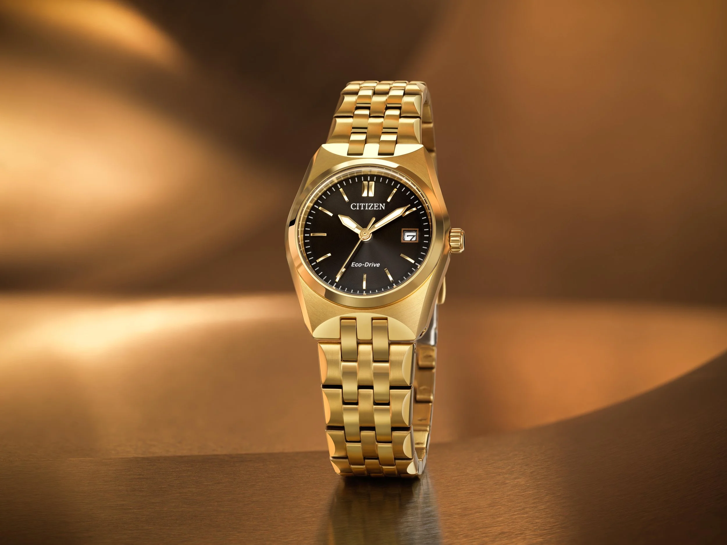 Gold Citizen Eco-Drive wristwatch with a black dial on a gold background.