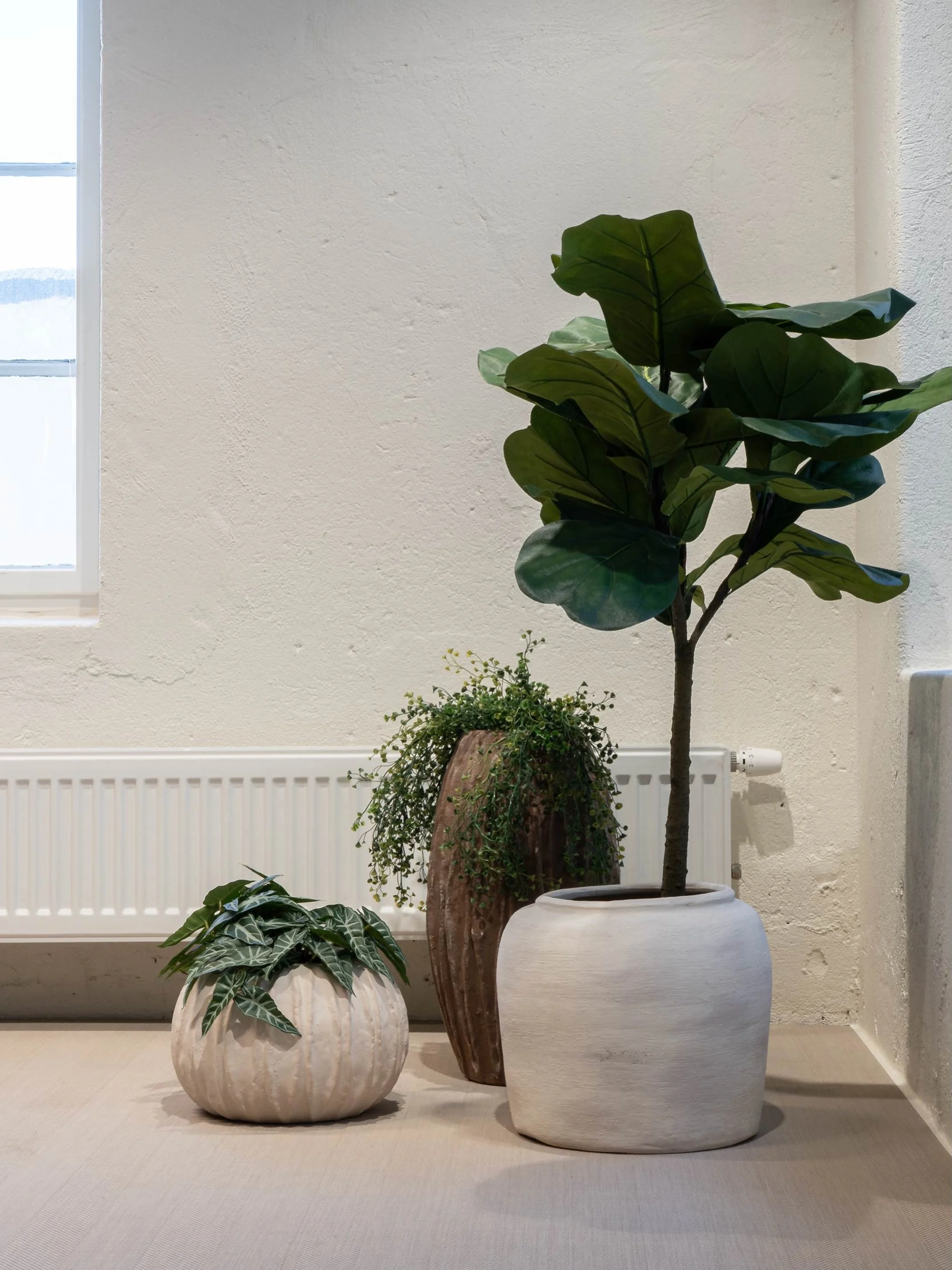 Dempede jordtoner, gr&oslash;nne planter og kalkede vegger mot et sandfarget gulv. Materialpaletten i du Nord er satt sammen med 2tec2 Herringbone Dune som den varme, samlende basen.
