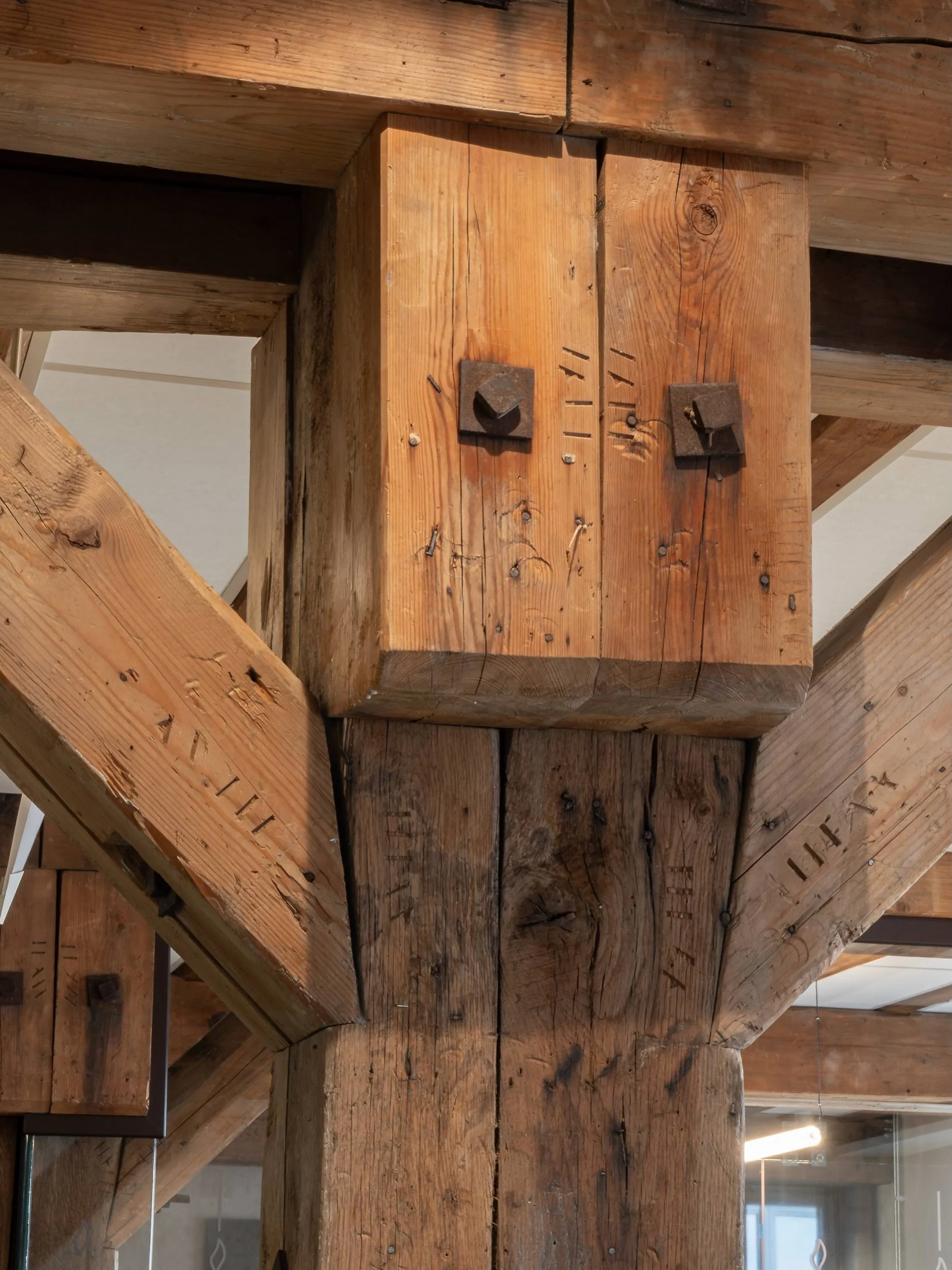 Detaljene som forteller historien: h&aring;ndmerkede t&oslash;mmerstokker med smidde beslag, bevart fra det opprinnelige bygget i Dronningens gate 13. Selvaag Eiendom gjenreiser kvartalet med respekt for det gamle, og lar materialene fra to ulike &ar