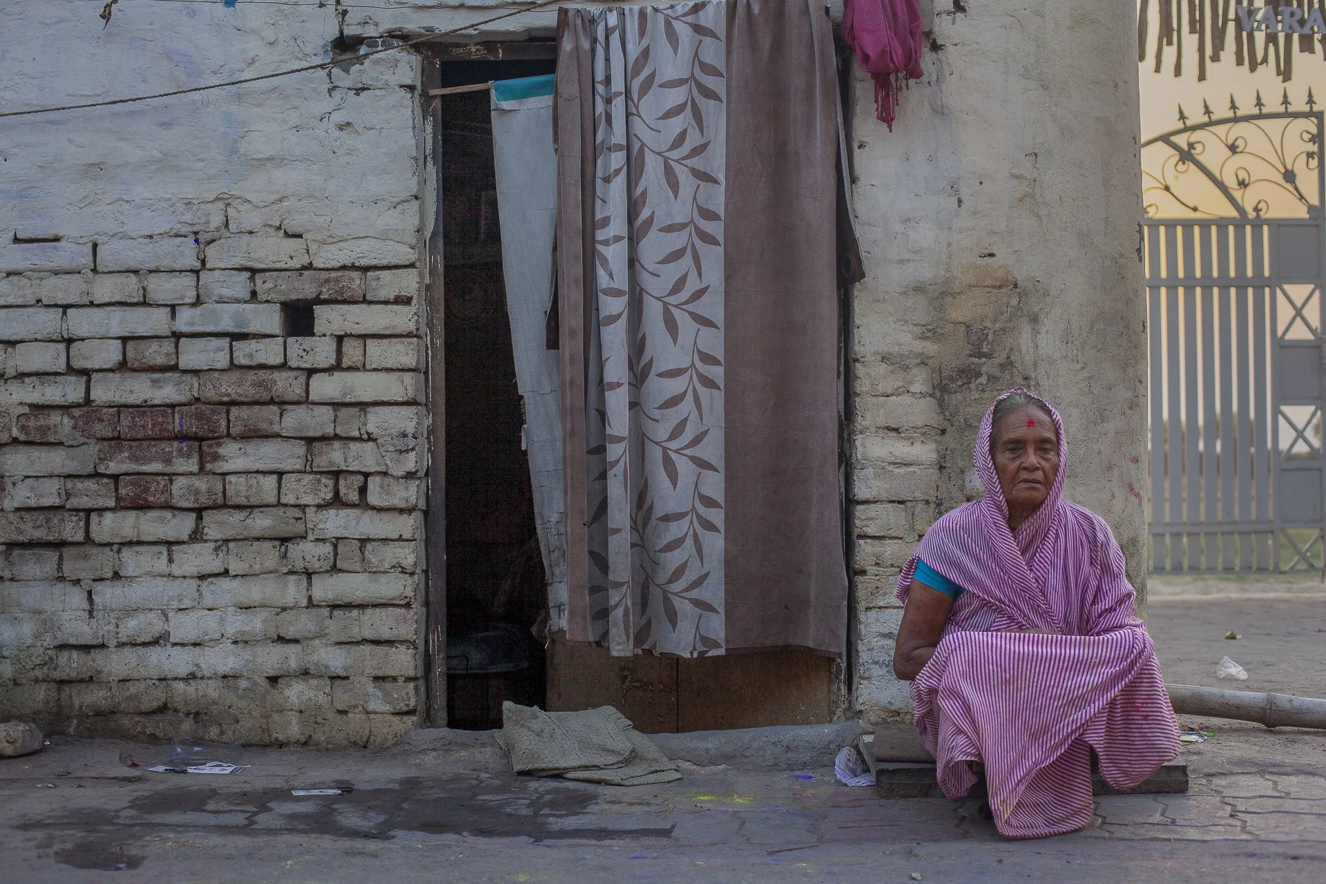 old woman on the doorstep of her home, varanasi