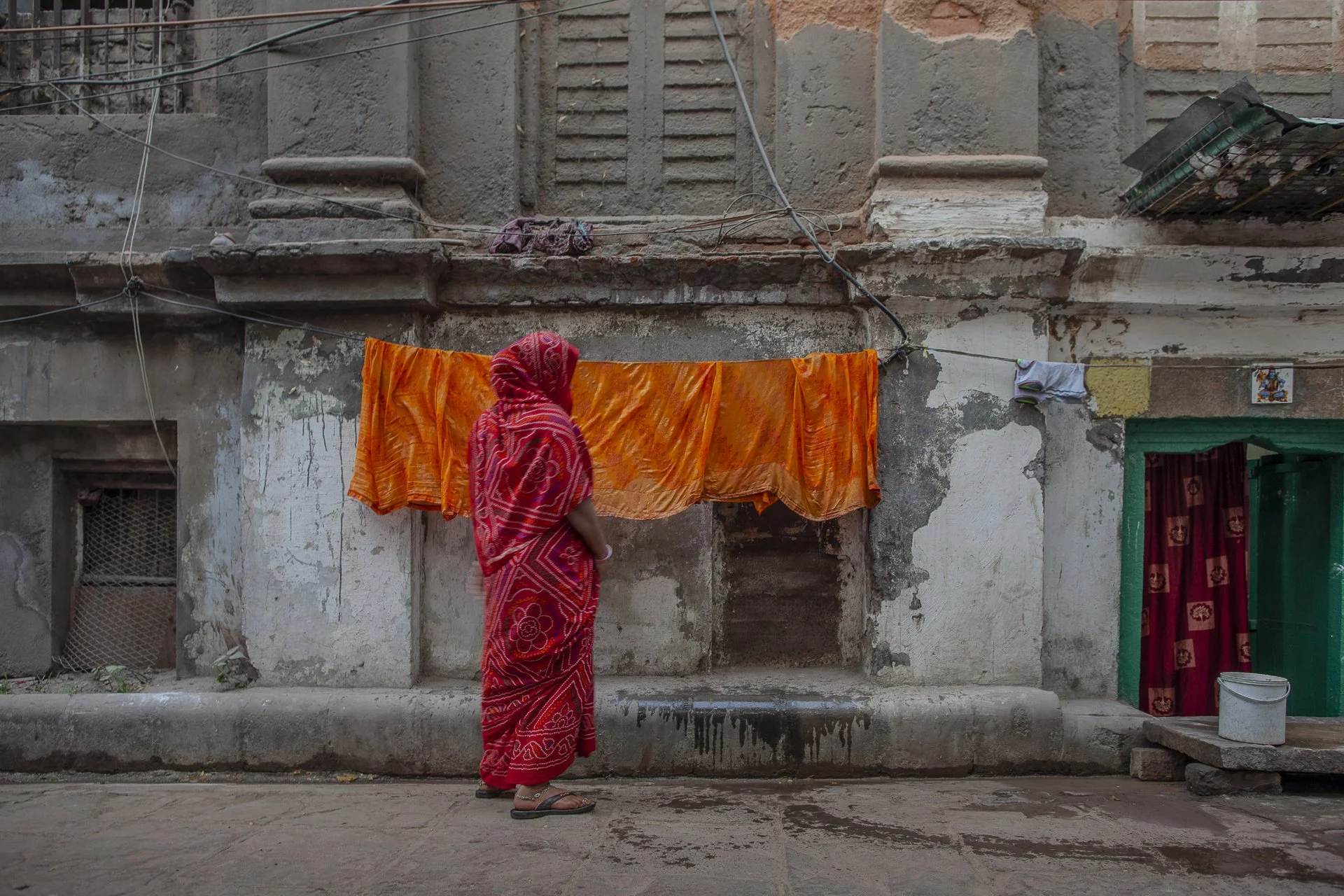 young woman in red sari hanging laundry to dry