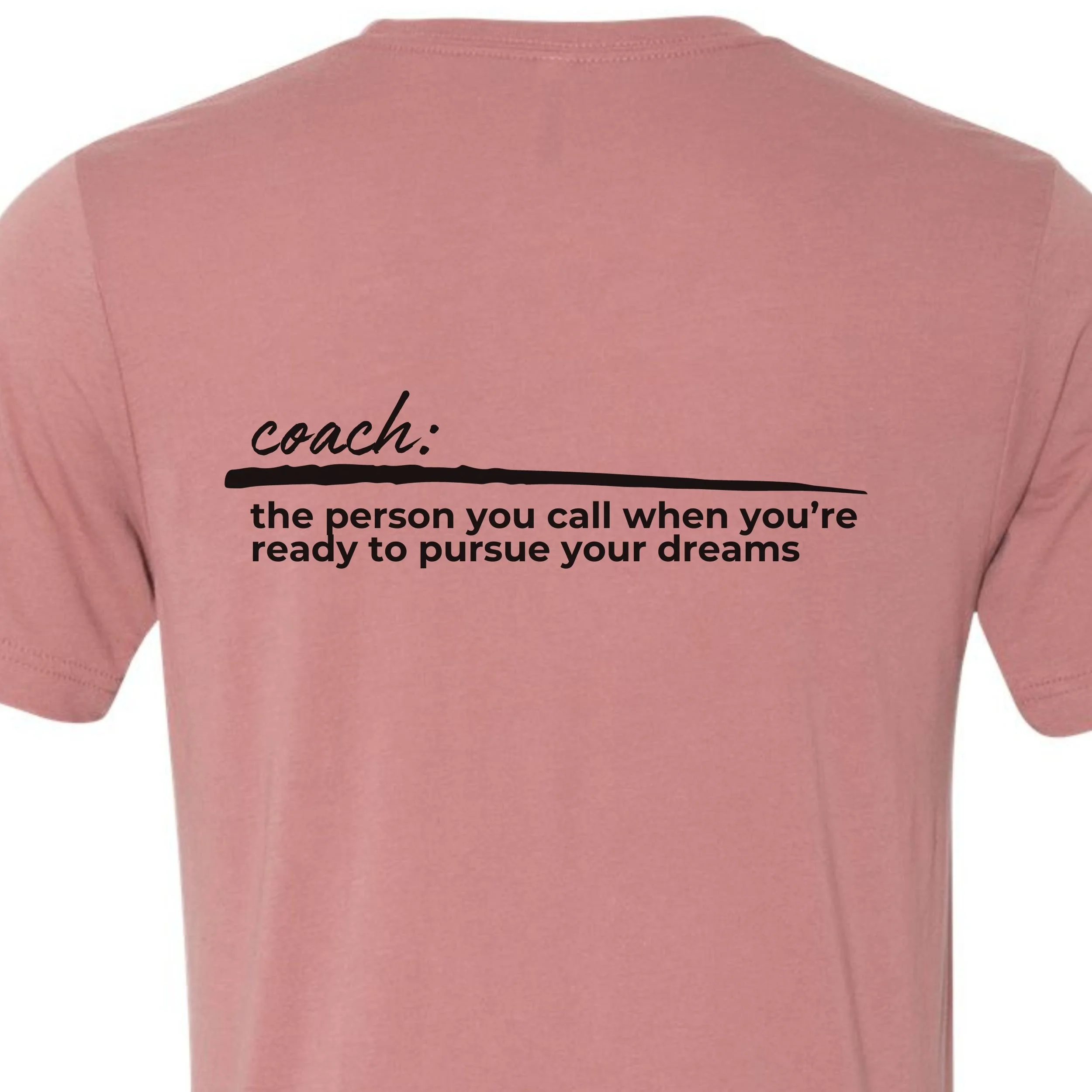 back of a mauve tee shirt with black text that says coach over a black dash over the person you call when you're ready to pursue your dreams