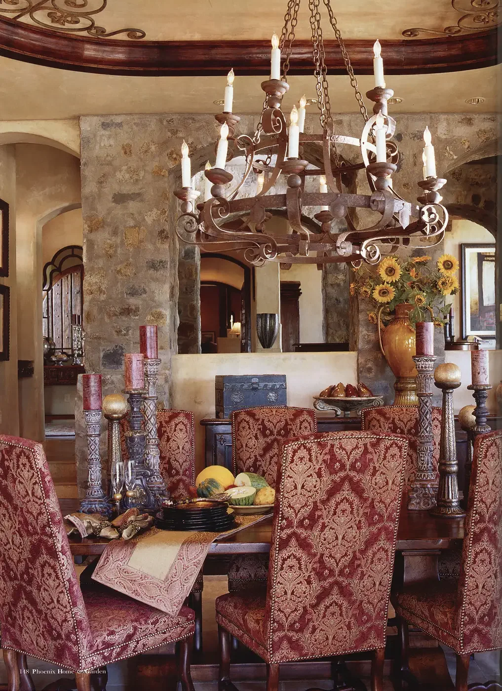  A wood band and ironwork highlight the dining room’s ceiling. Tapestry chairs in warm tones and a prominent chandelier also vie for attention.  