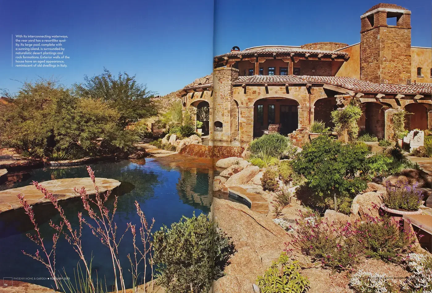  With its interconnecting waterways, the rear yard has a resort-like quality. Its large pool, complete with a sunning island, is surrounded by naturalistic desert plantings and rock formations. Exterior walls of the house have an aged appearance, rem
