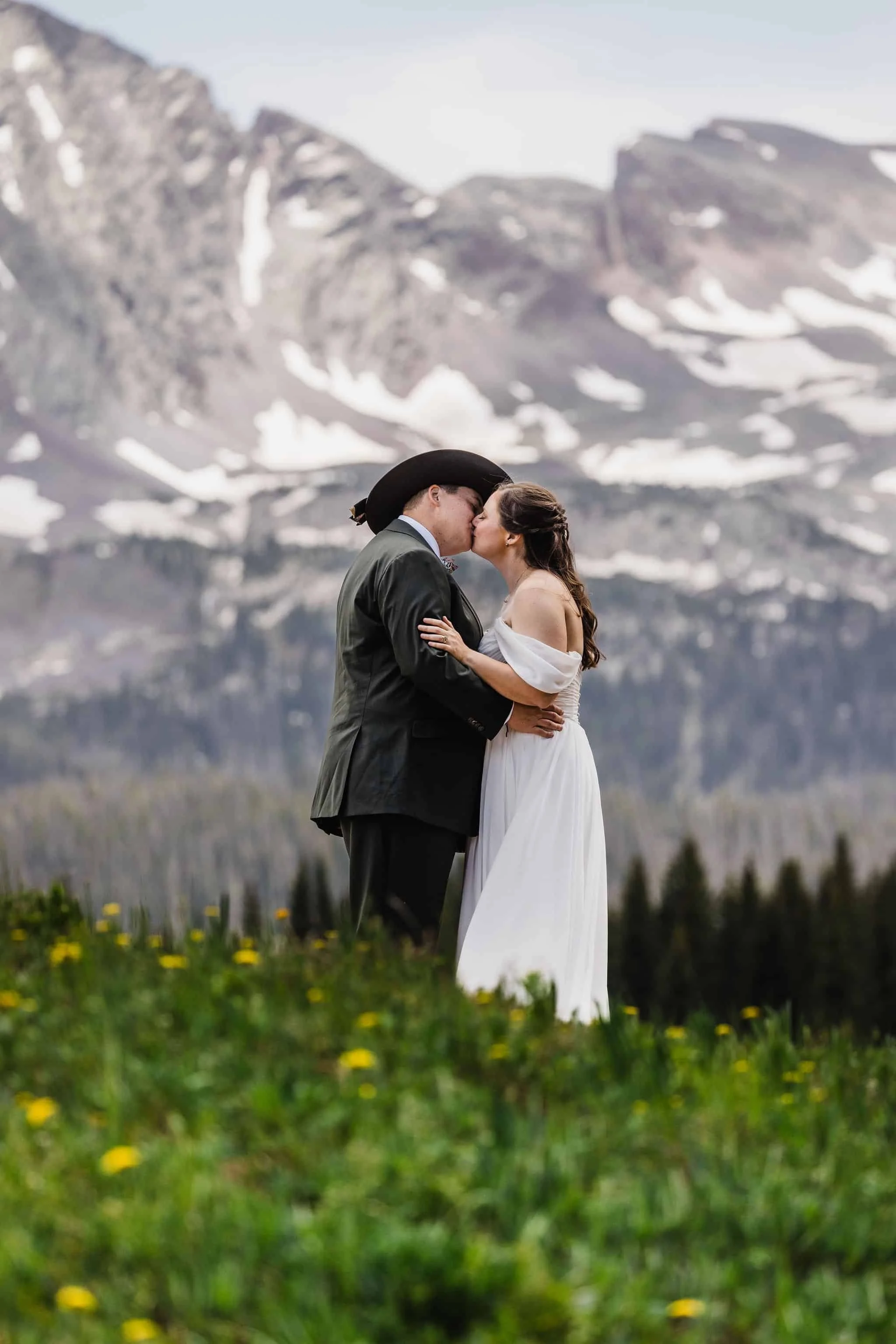 A couple kisses in front of a mountain