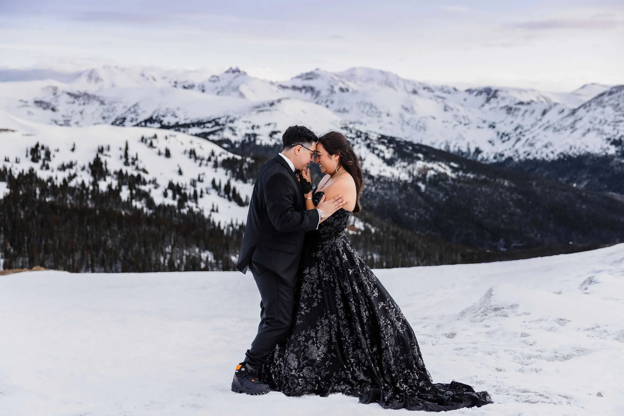 A couple hugs while standing in the snowy mountains