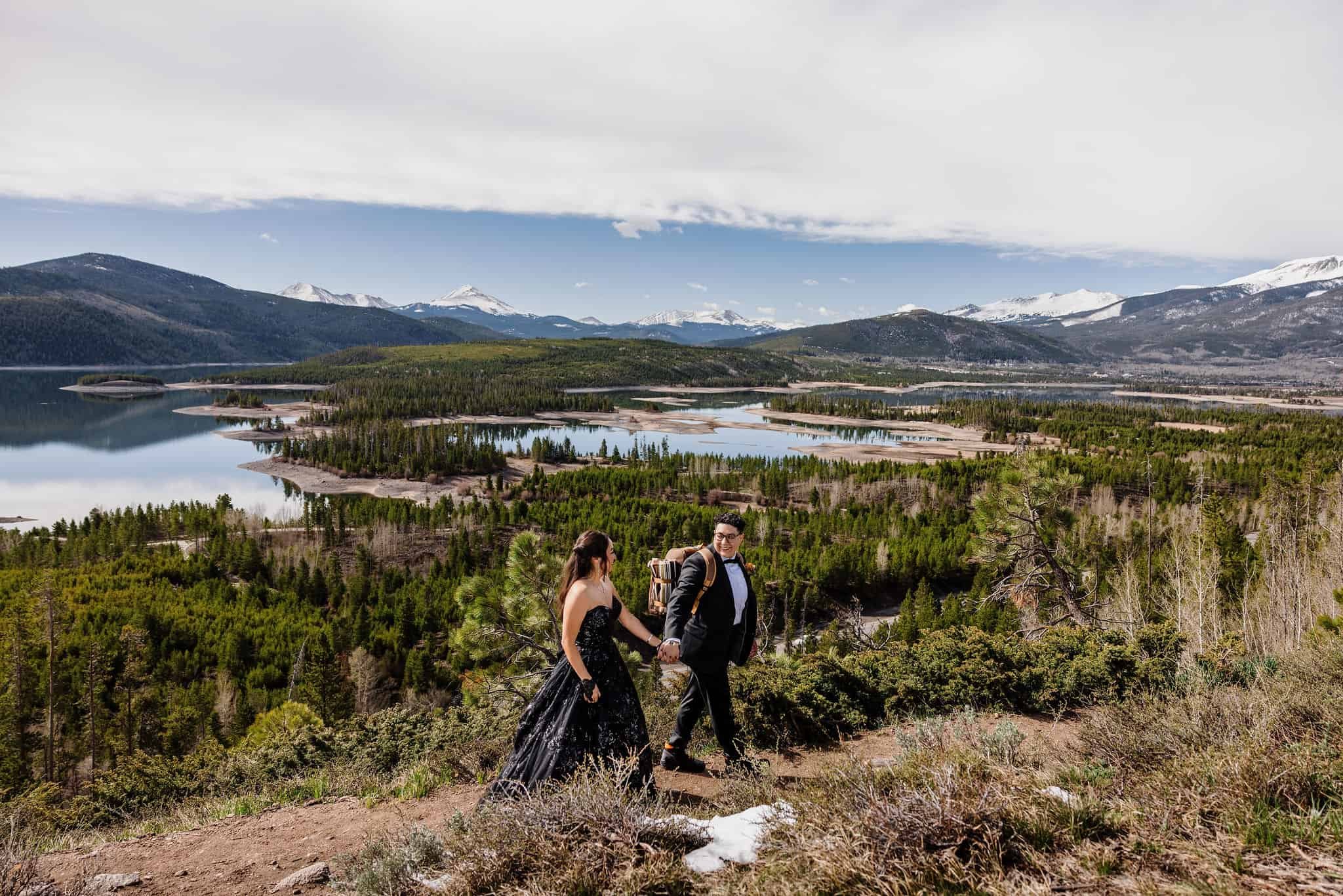 A couple holds hands and hikes down a mountain trail