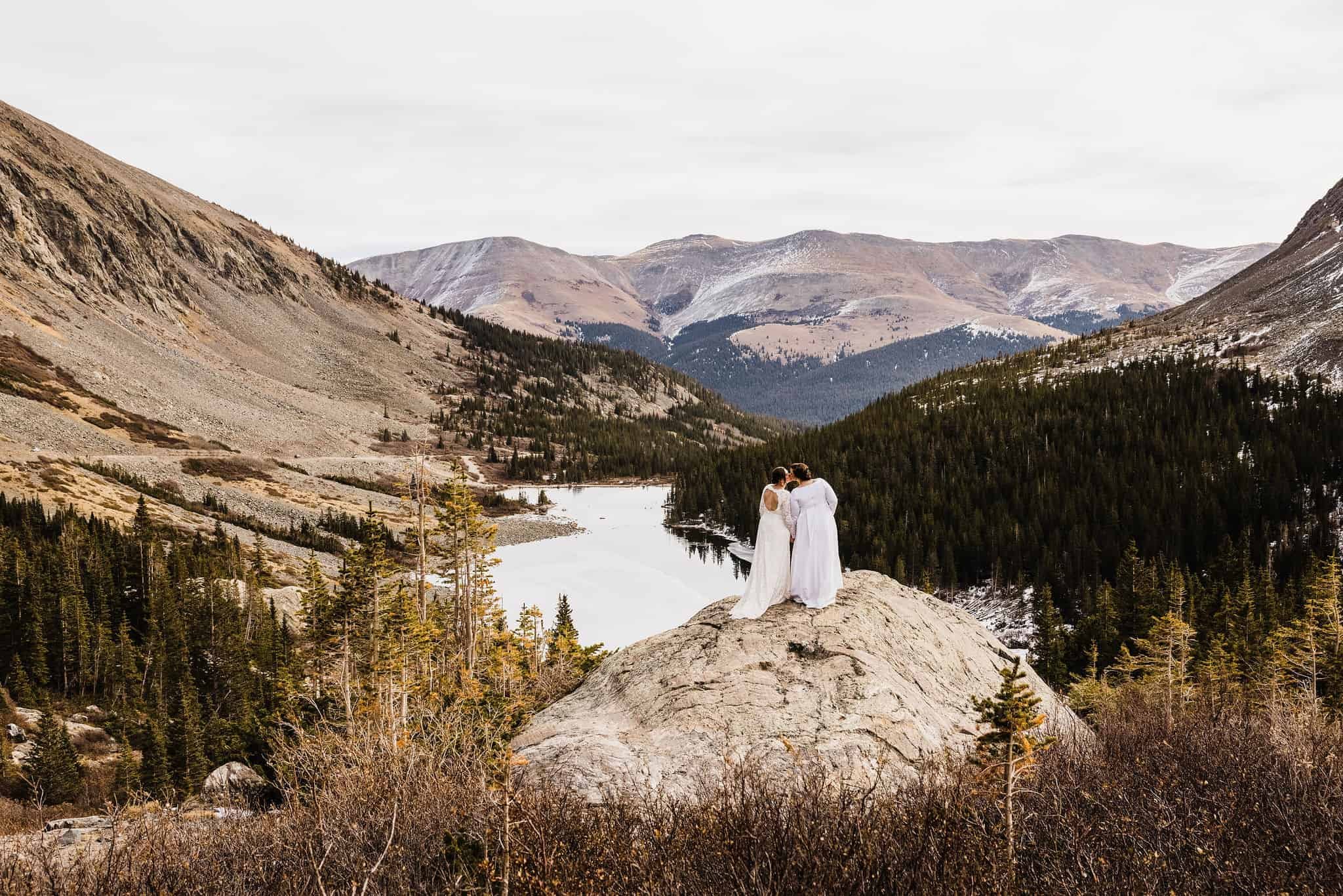 A couple stands above a mountain lake
