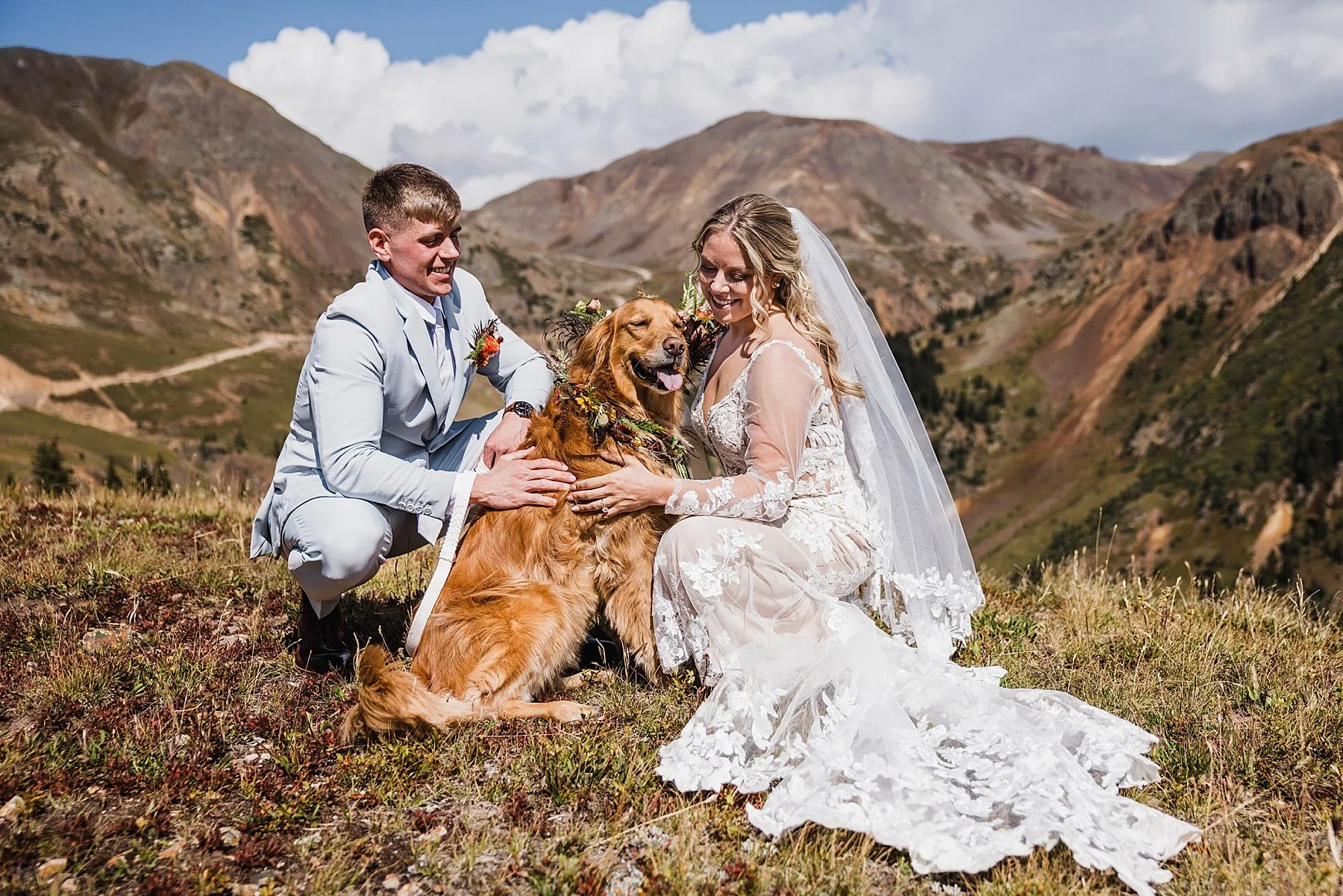 A couple kneels with their dog