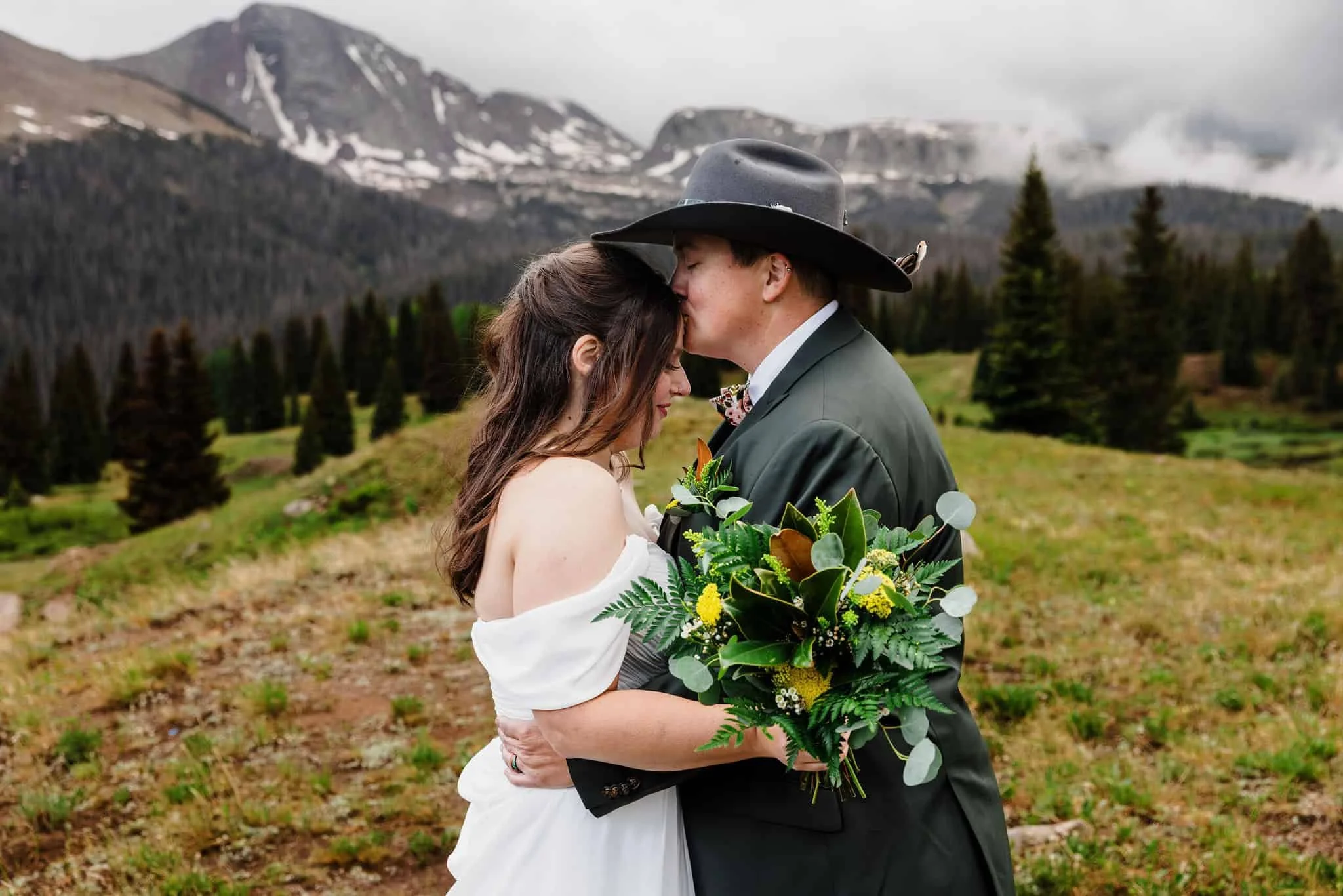 A couple kisses while in foggy mountains