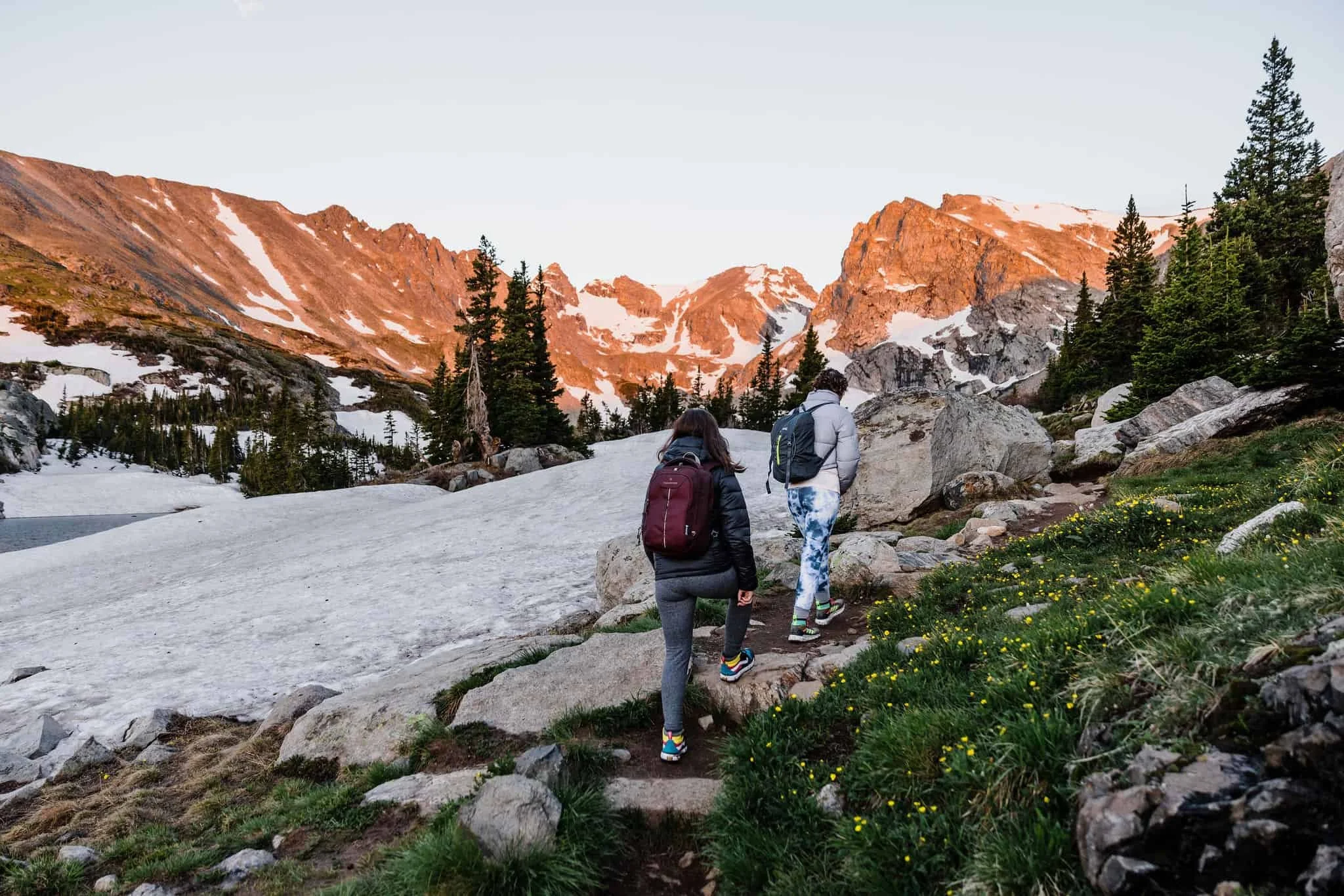 A couple hikes toward a mountain at sunrise