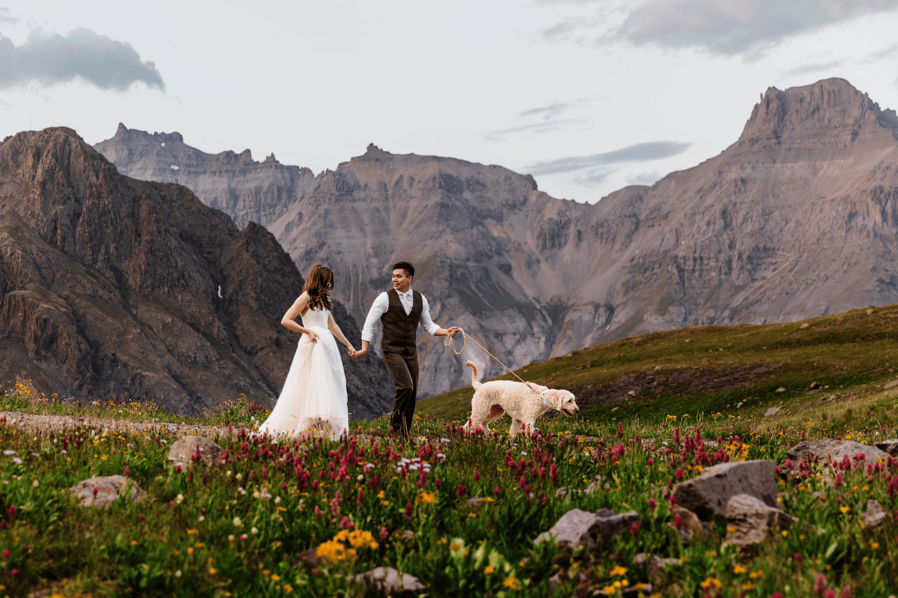 Elopement photo of a couple walking their dog in the mountains