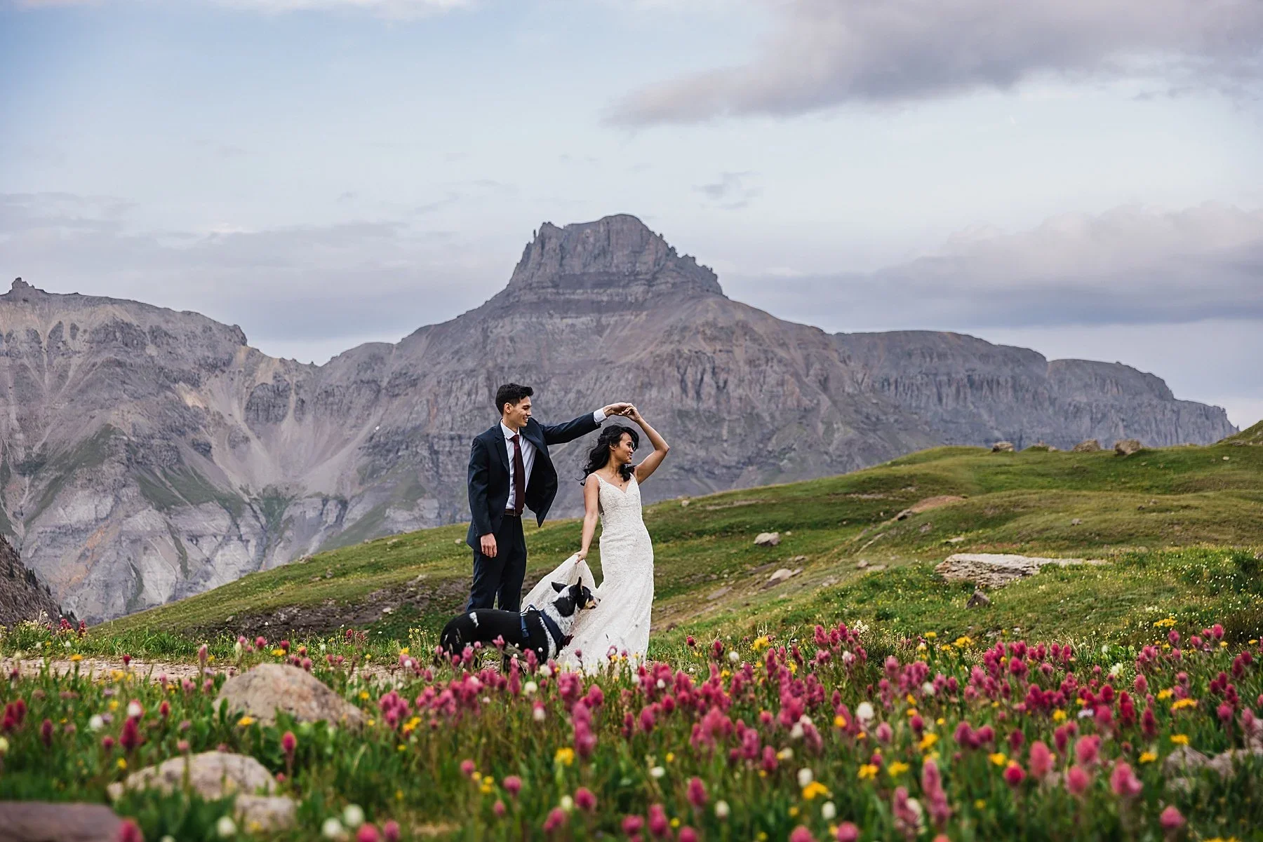 A couple dances at sunset in the mountains with their dog