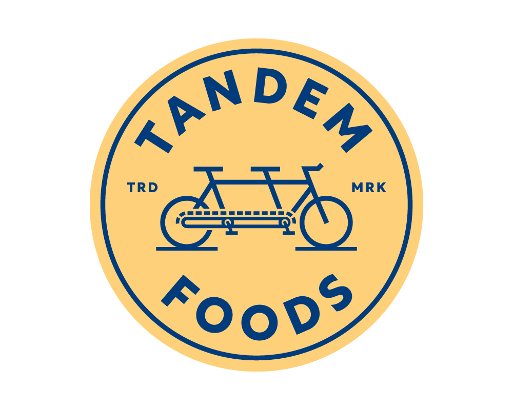 Blue and gold Tandem Foods emblem with tandem bike artwork.