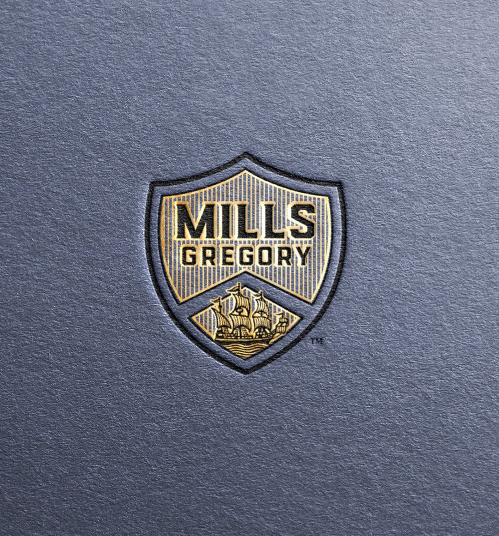 Mills-Gregory shield logo embossed into toothy blue paper.