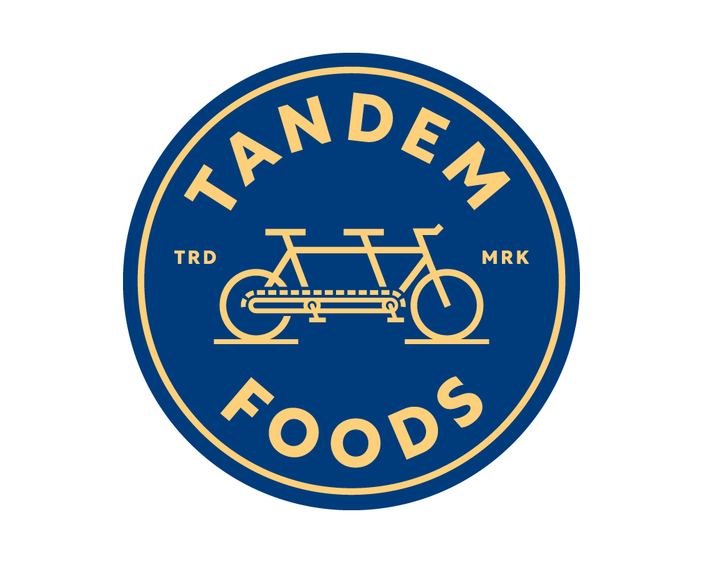Gold and blue Tandem Foods emblem with tandem bike artwork.