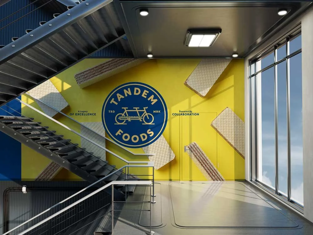 Office stairwell with bright colored graphic  wall featuring blue and gold Tandem emblem over photo of wafer bars.