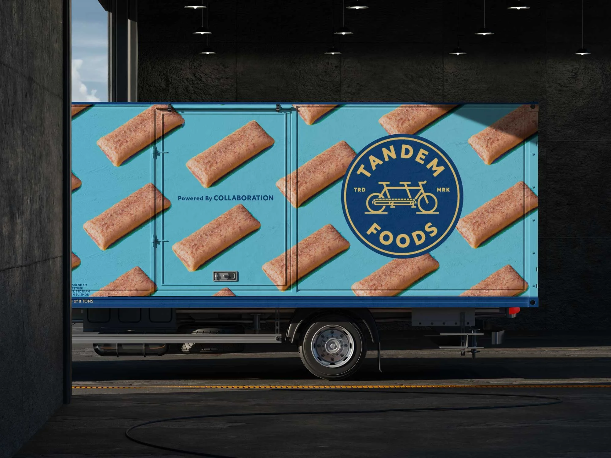 Box truck wrapped with brand graphics including blue Tandem emblem over pattern of nutrition bars over bright blue background.
