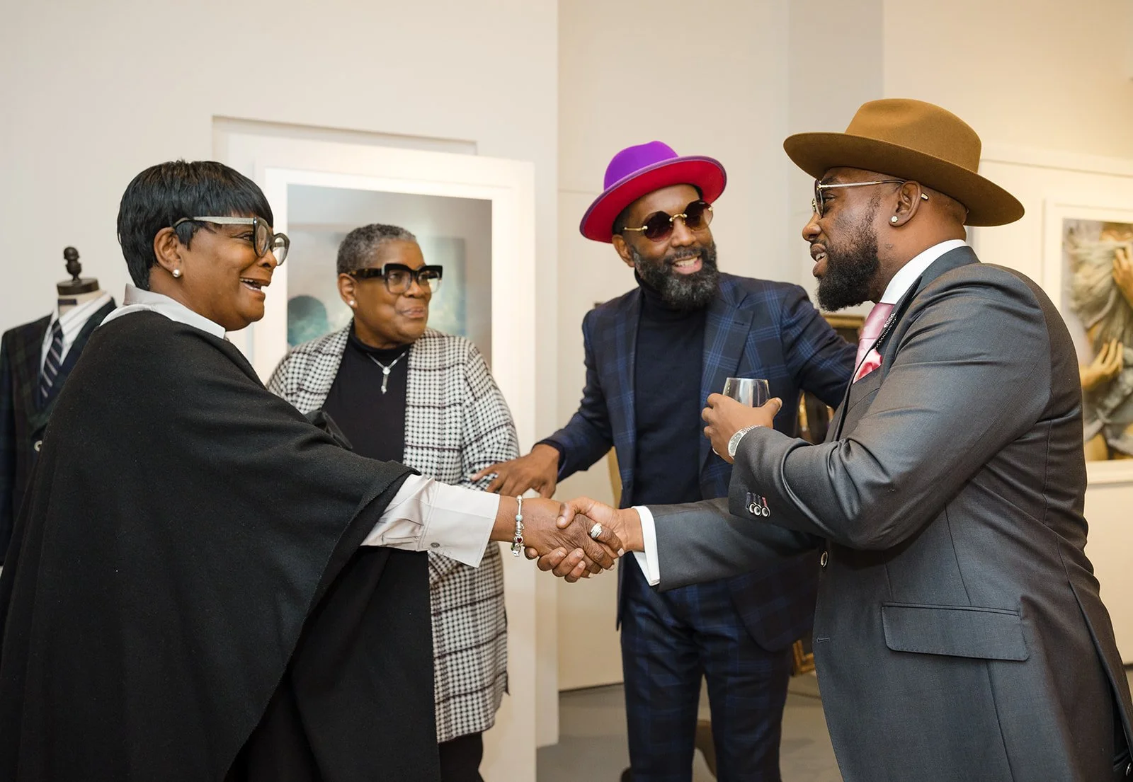 People in formal attire greeting each other at an art gallery.