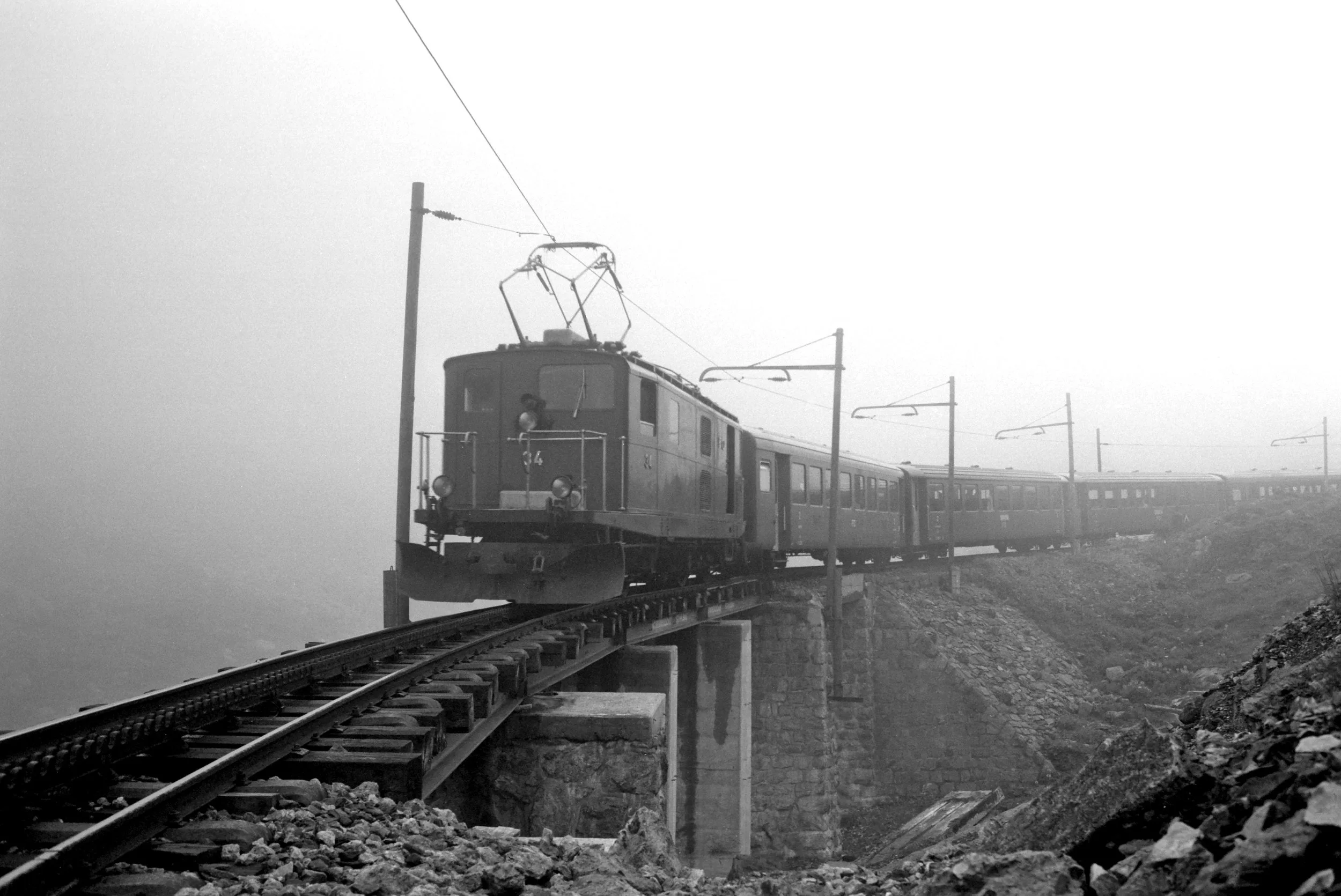 HGe 4/4 34 mit Schnellzug Chur - Brig im Nebel unterhalb Gletsch. **