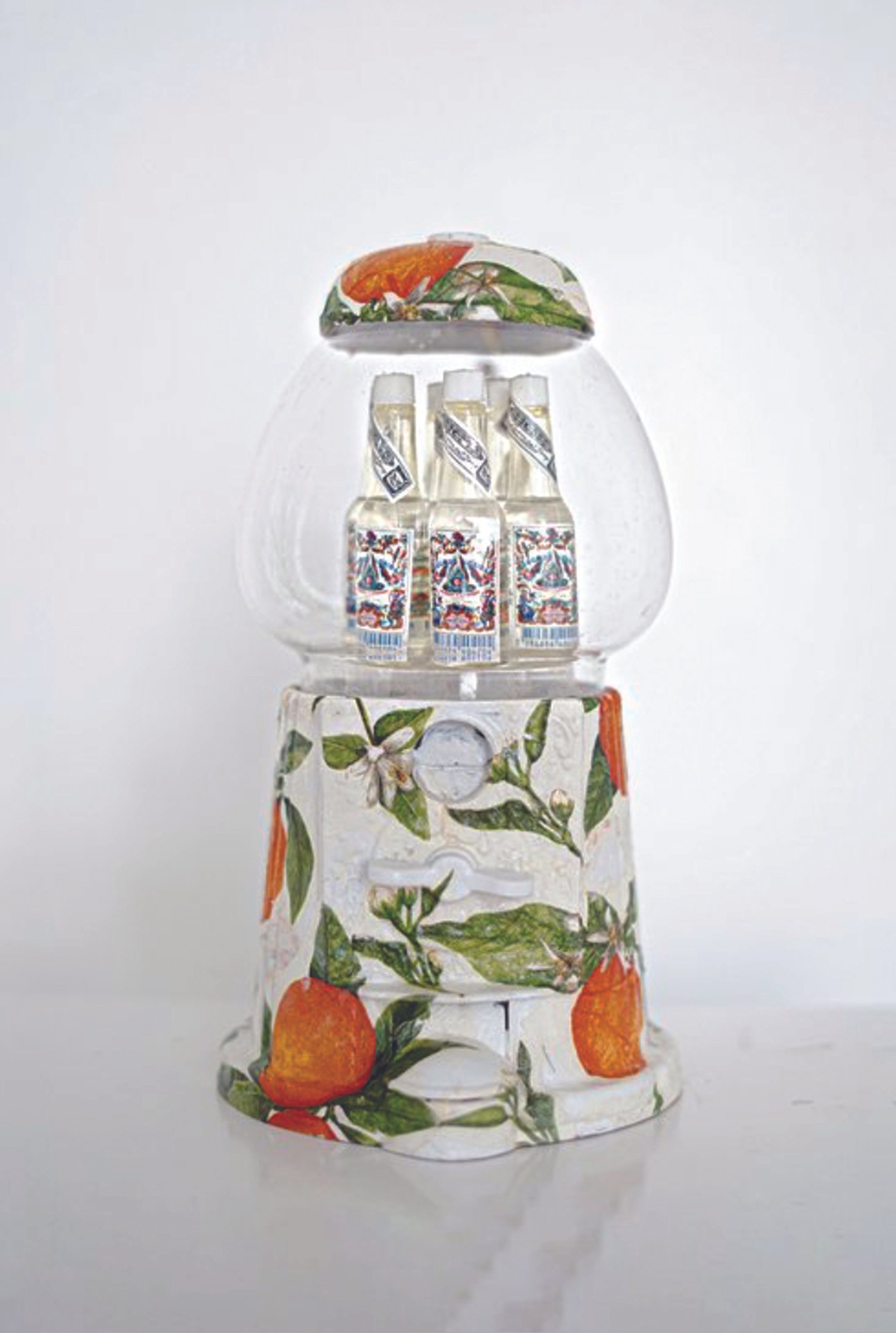 A vending machine with a floral and fruit design on its surface, containing three bottles of a clear beverage.