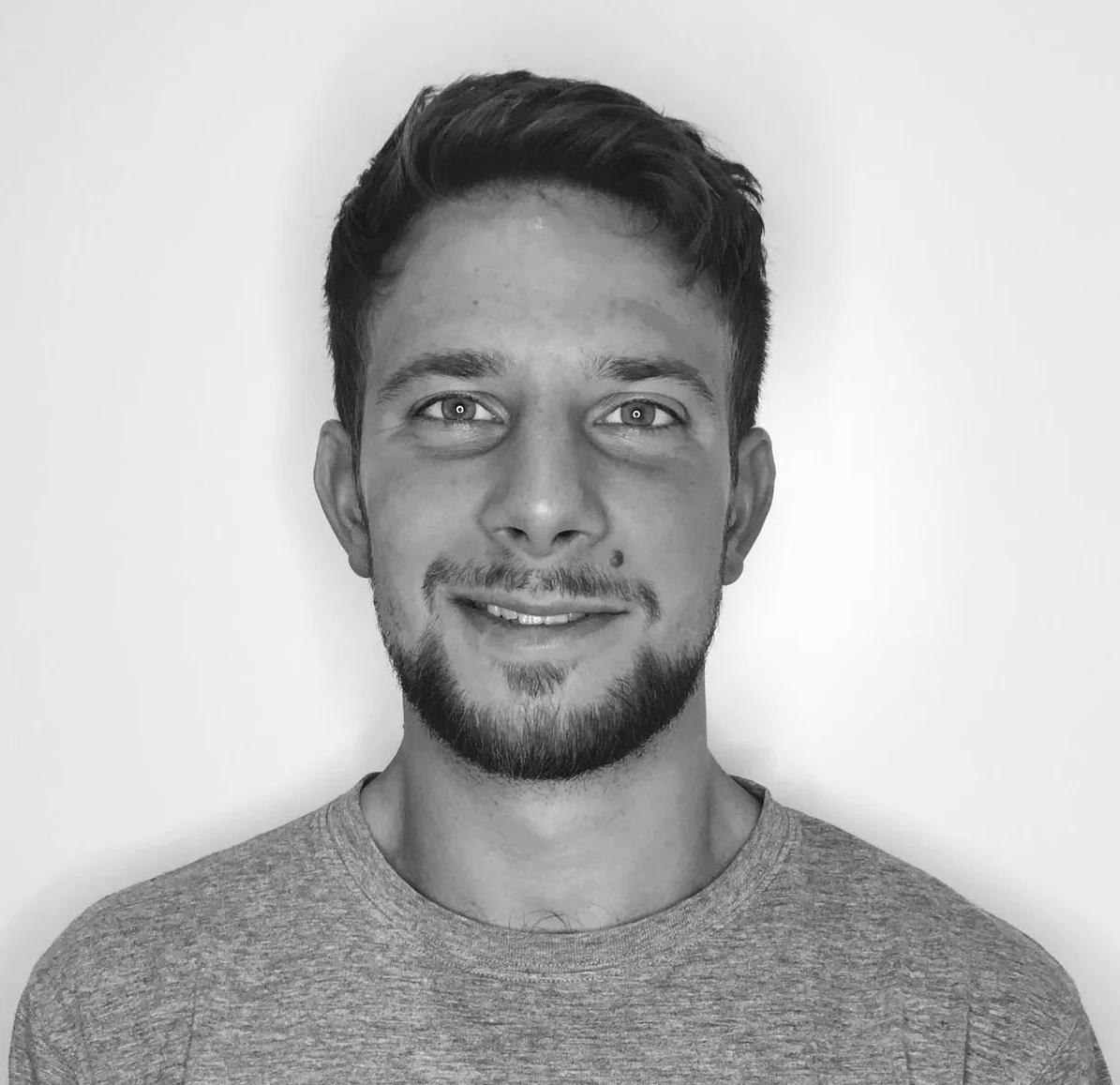 Mustavalkoinen valokuva miehestä, jolla on parta ja lyhyet hiukset.