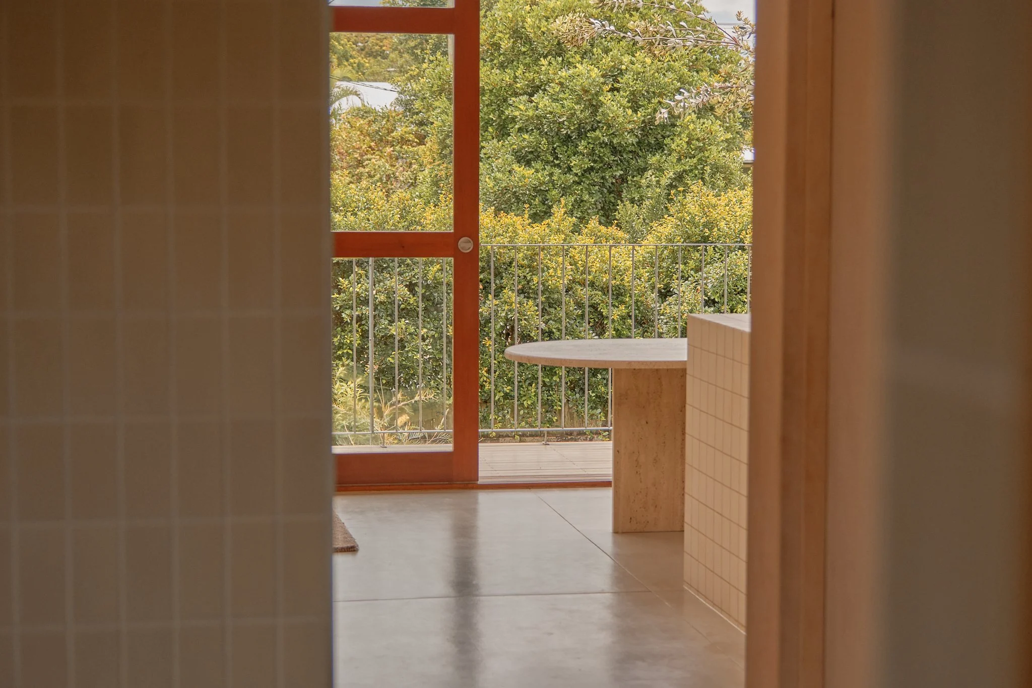 Door opening to a balcony with trees in the background.