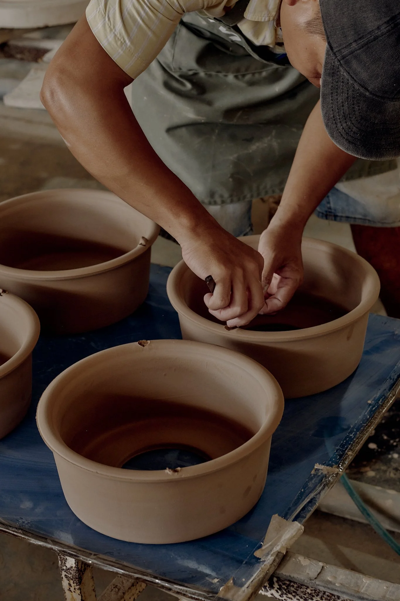A person shaping a clay pot on a pottery wheel in a workshop.