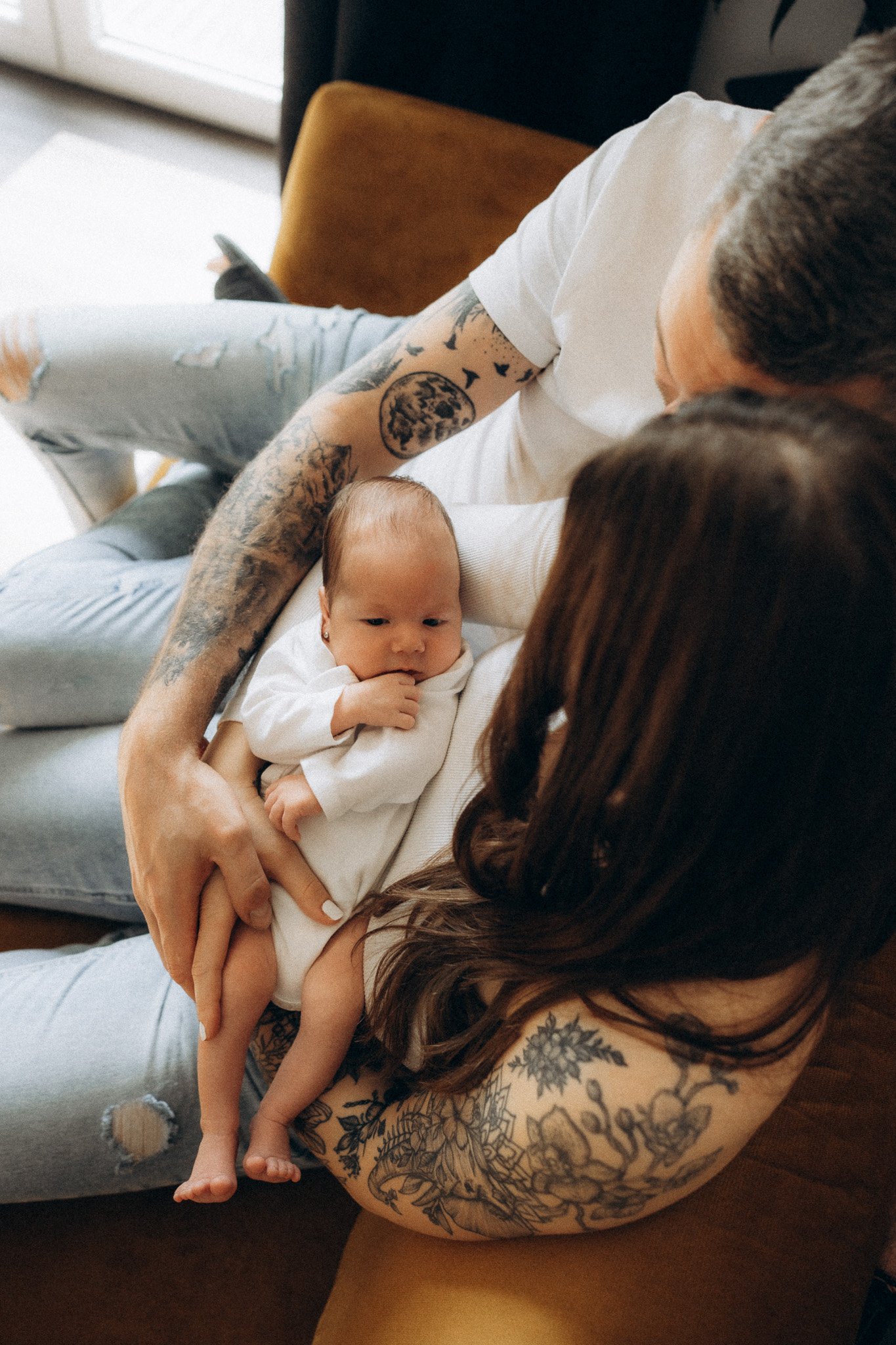 Rodina sedící spolu na gauči při novorozeneckém focení