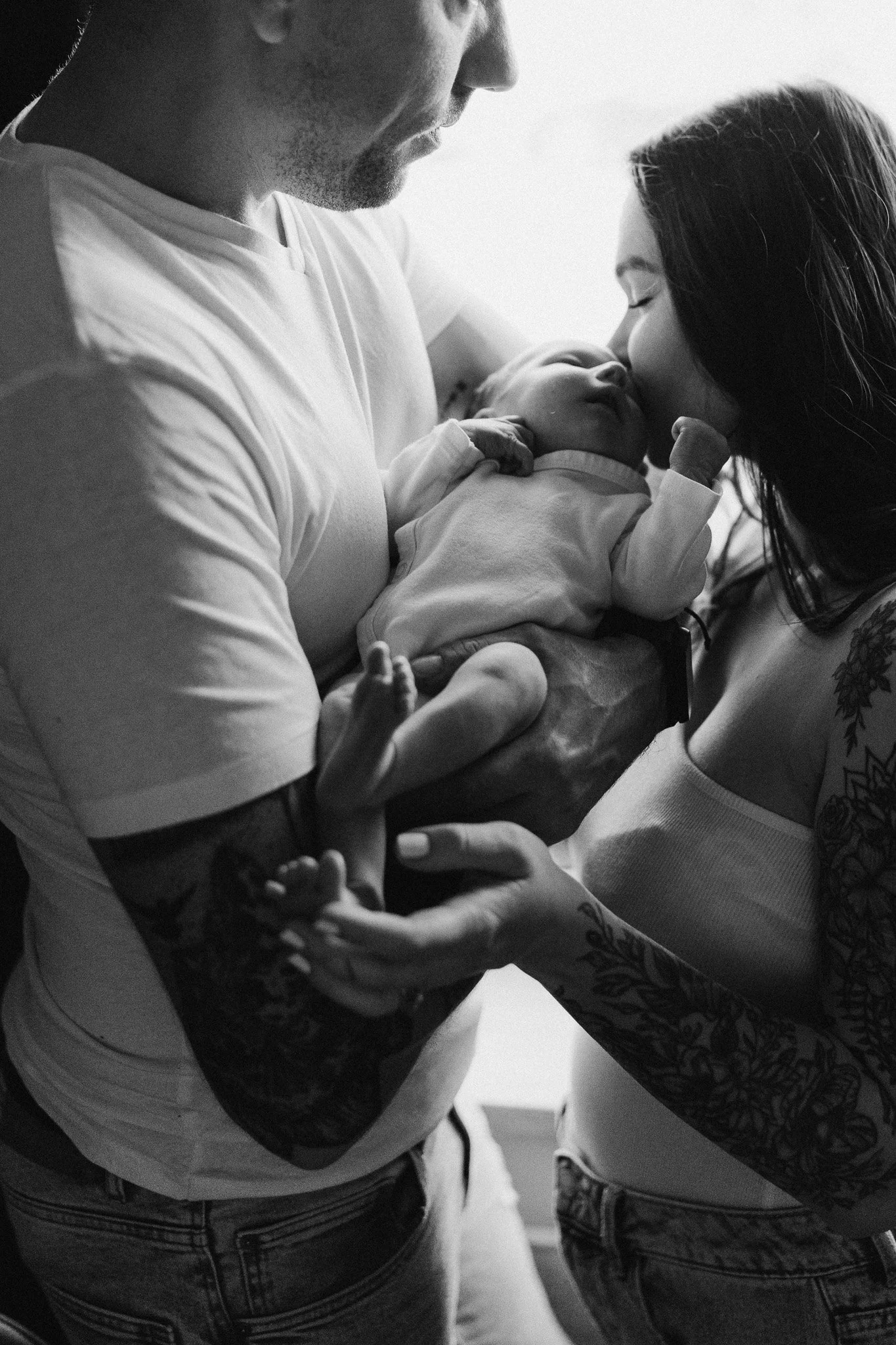 Maminka dává pusinku novorozenému miminku při focení doma